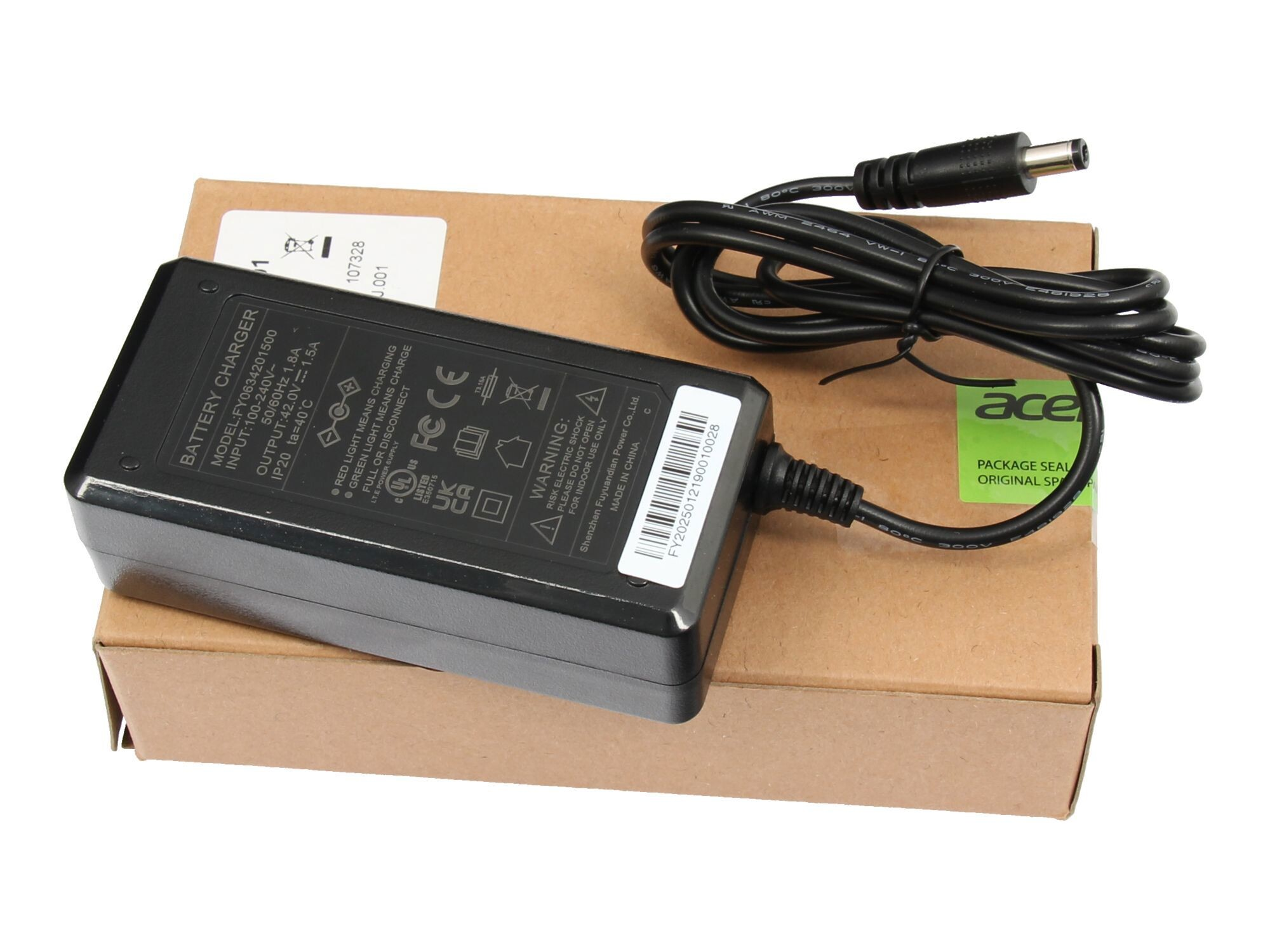 Ein schwarzes Acer Netzteil mit Kabeln und Beschriftungen liegt auf einem Karton.