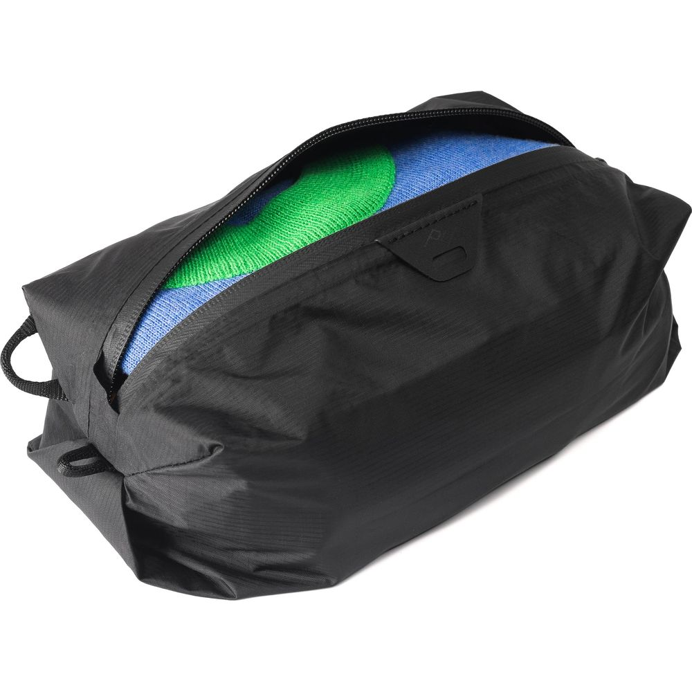 Zwarte tas met open rits, blauwe en groene kleding erin.