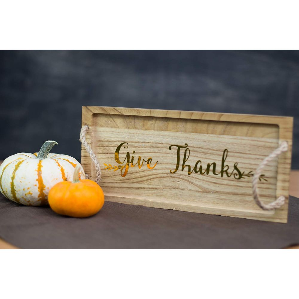 Holzschild mit „Give Thanks“ und zwei Kürbissen im Vordergrund.