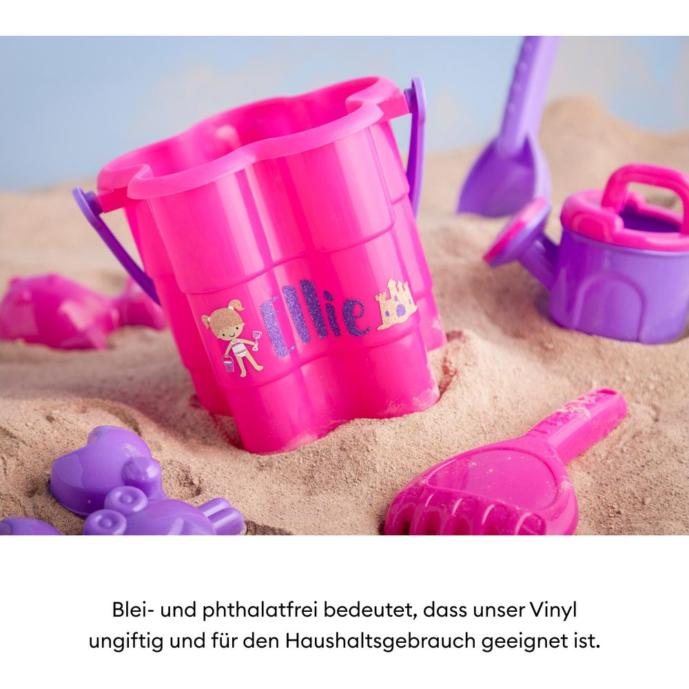 Pinker und violetter Spielzeug-Sandkasten-Set mit Eimer, Gießkanne und Schaufeln im Sand.
