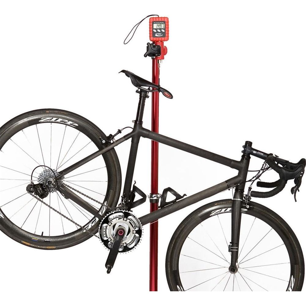 Una bicicletta da strada nera è appesa a una bilancia rossa con display digitale.