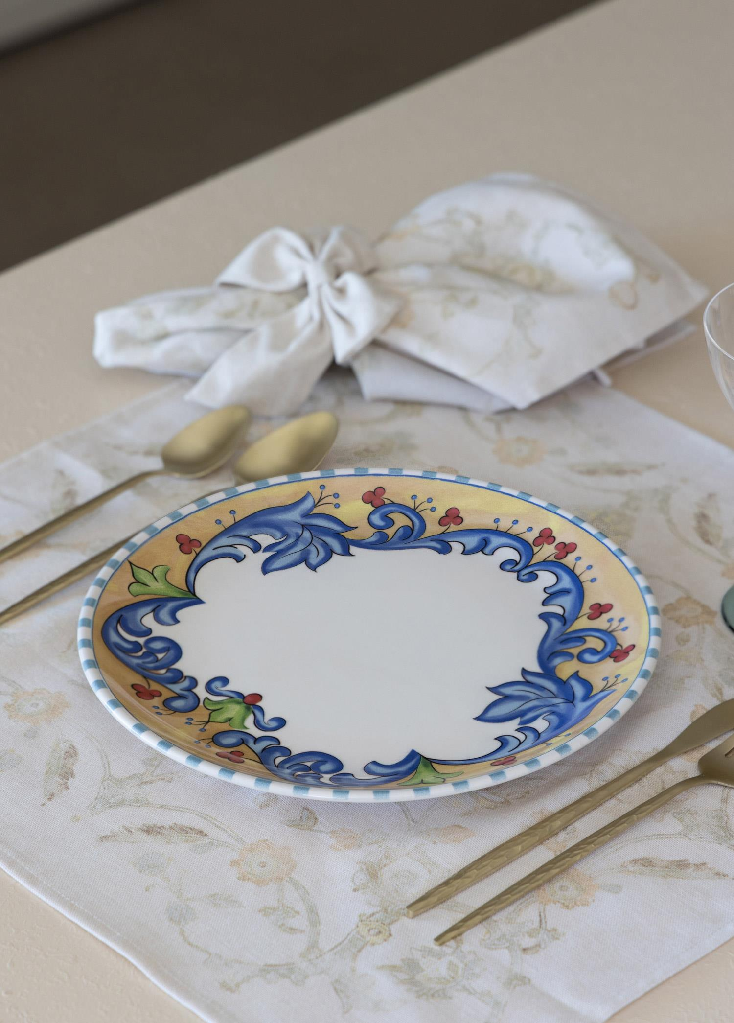 Altın rengi kaşıklara sahip masada mavi çiçek desenli oval tabak.