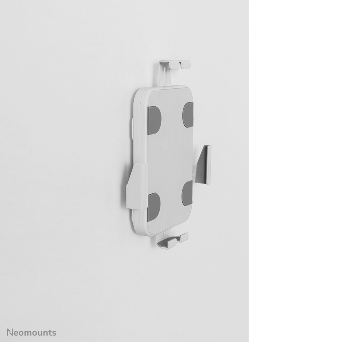 Un support blanc pour tablette avec des coussinets en caoutchouc gris est monté sur un mur blanc.
