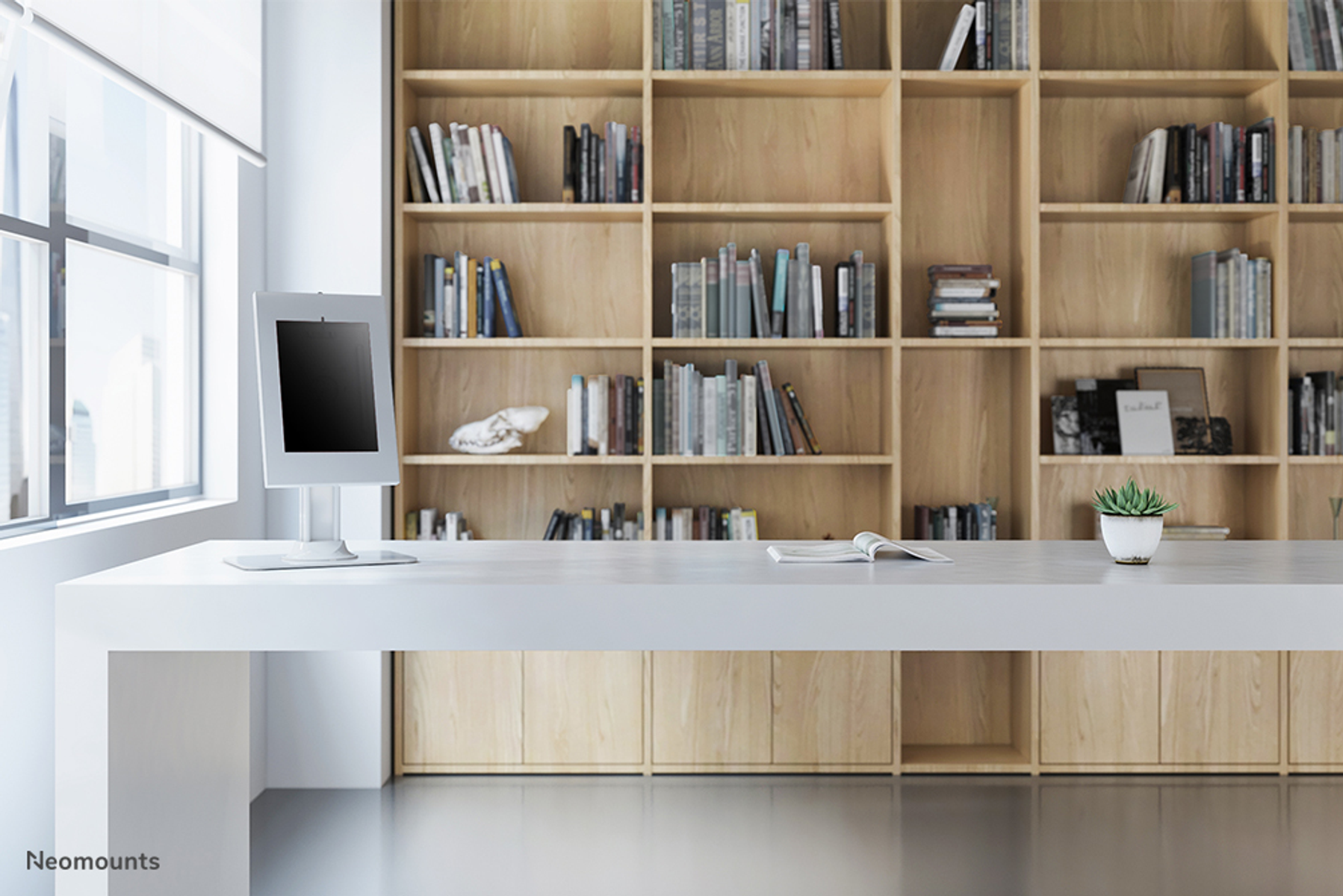Bureau moderne avec un bureau, une tablette et une grande bibliothèque remplie de livres.