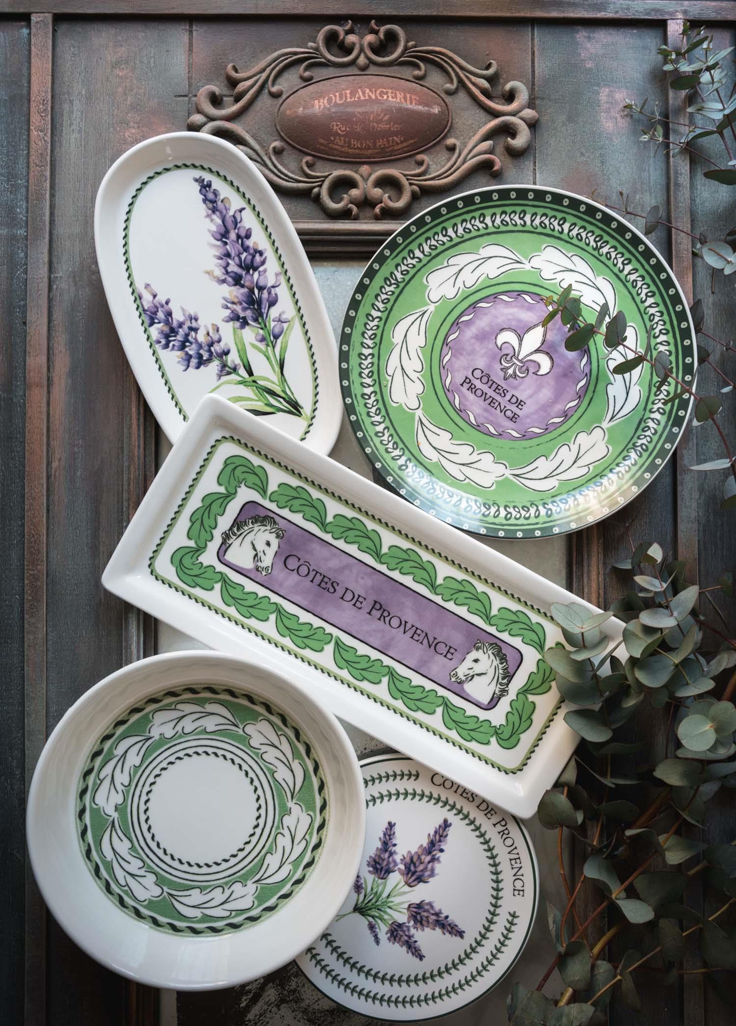 Rustik arka plan üzerinde lavanta, at başı ve fleur-de-lis desenli seramik sofra takımı.