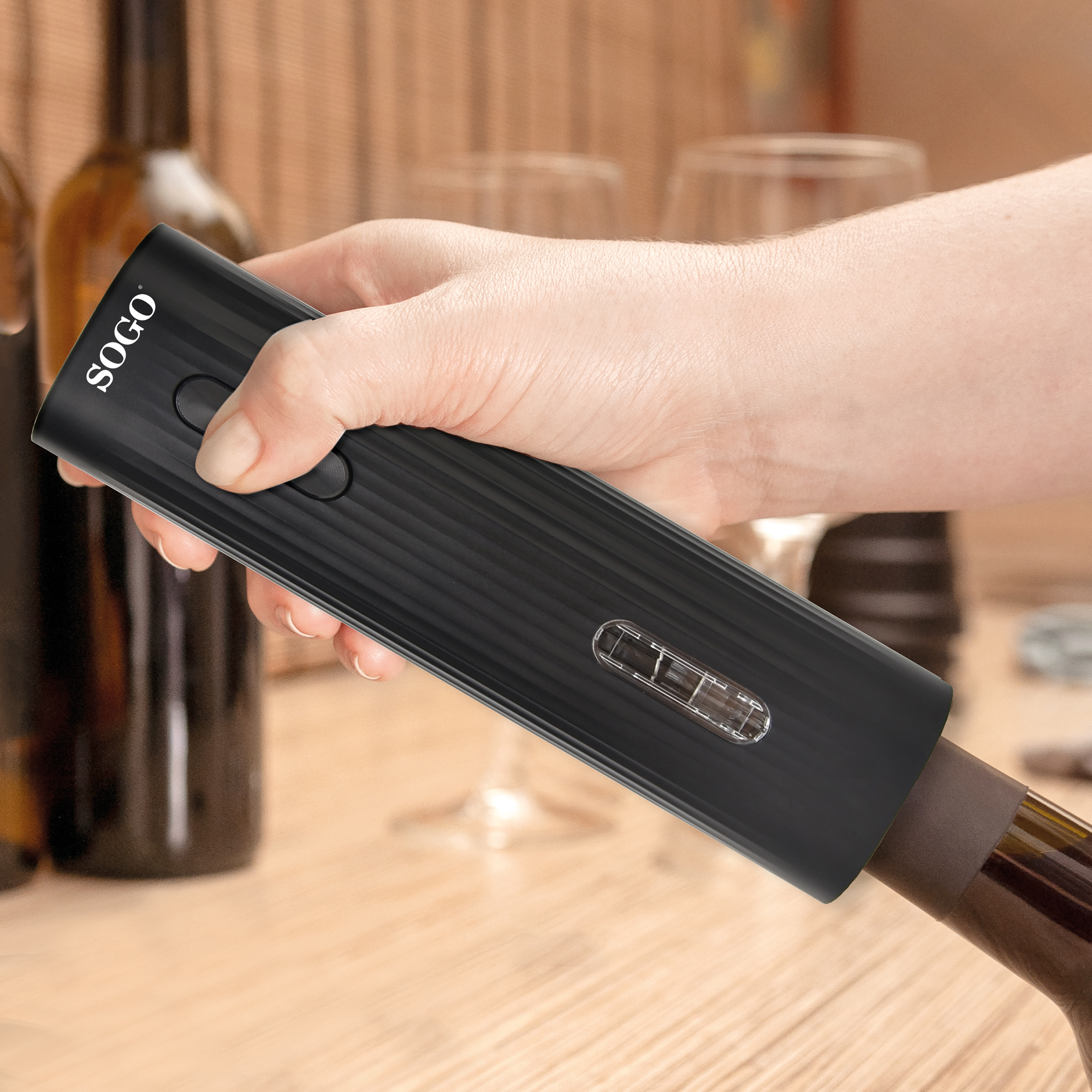 Una mano usa un cavatappi elettrico nero per rimuovere un tappo da una bottiglia di vino.