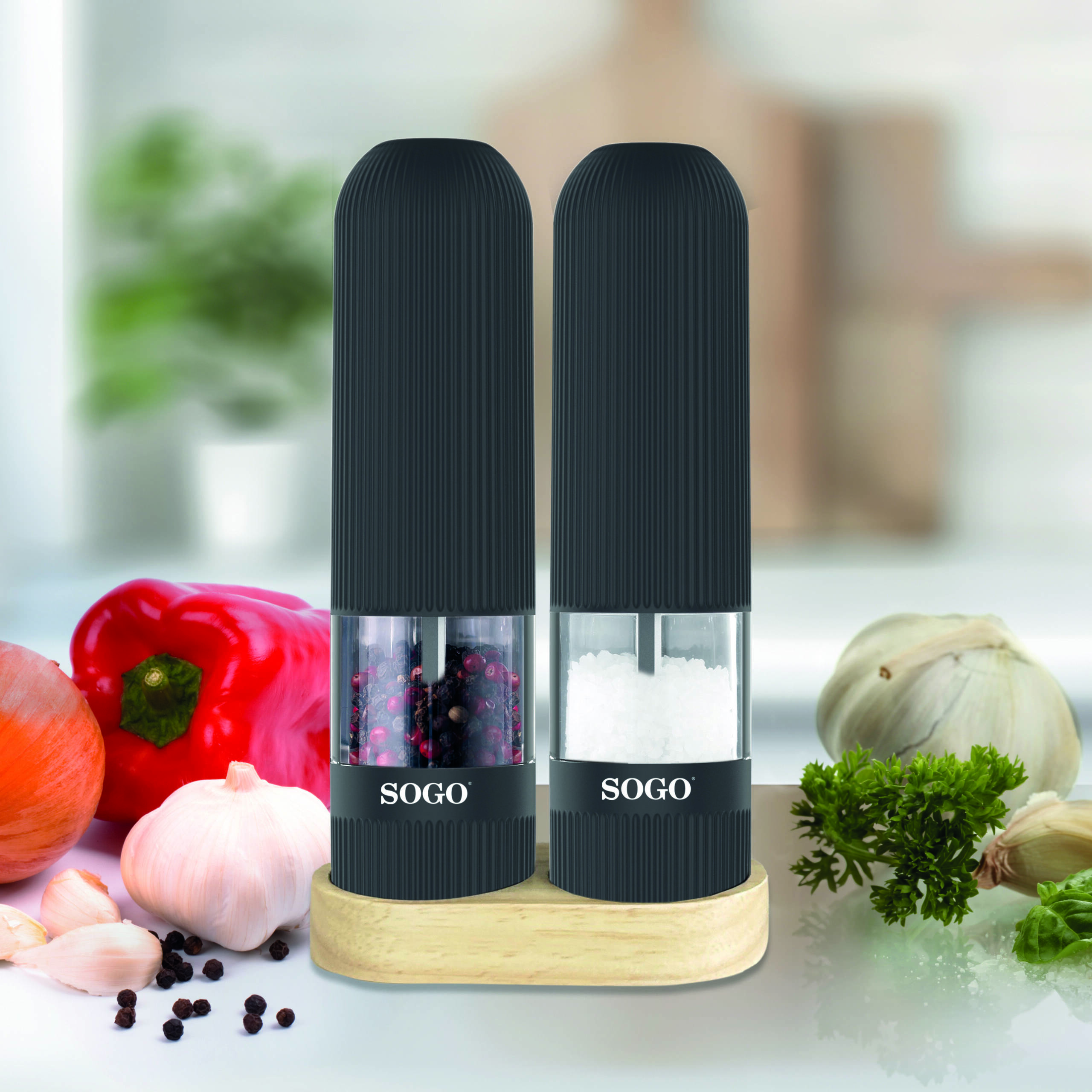 Due macinini SOGO su supporto in legno con spezie e verdure.