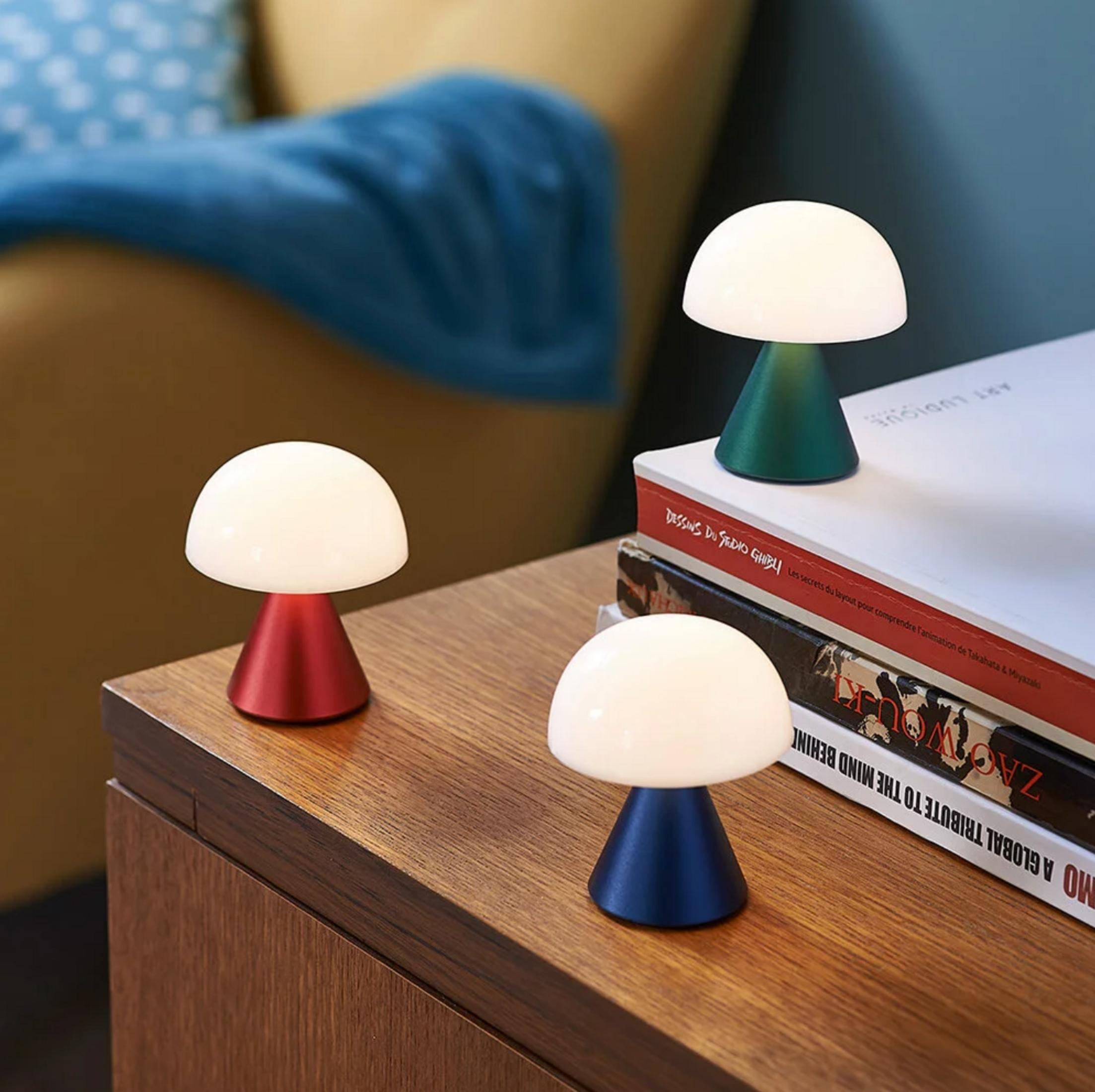 Drei Pilzförmige Lampen in Rot, Grün und Blau auf einem Holztisch.