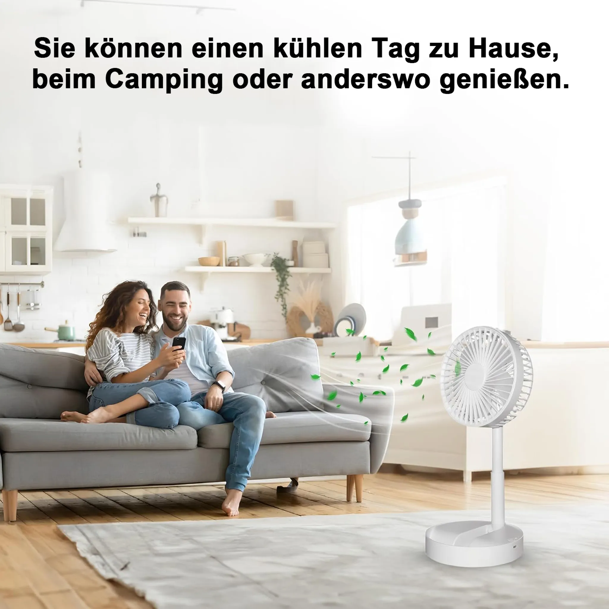 Ein Paar sitzt auf einem Sofa in einem hellen Raum, ein Ventilator steht daneben.