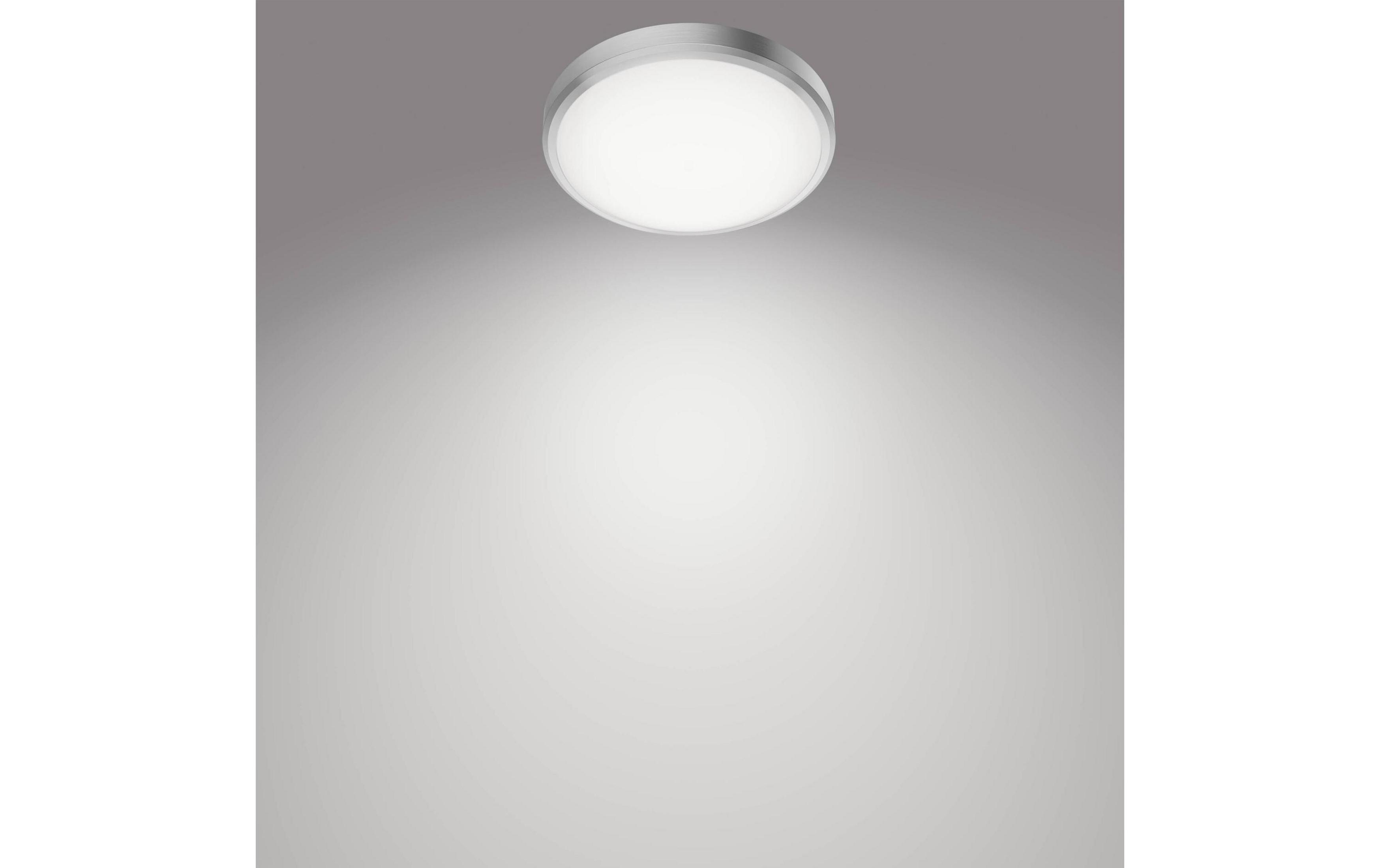 Un plafonnier rond à bordure argentée brille sur fond gris.