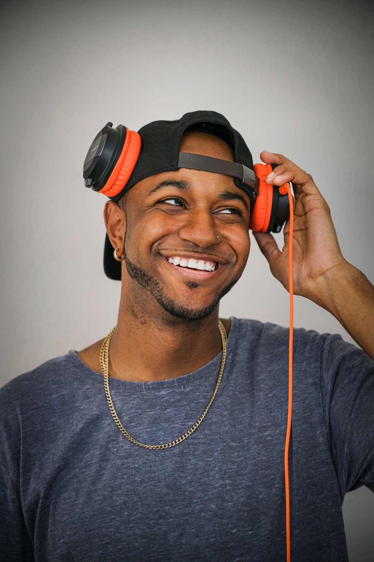 Mężczyzna w słuchawkach i czapce uśmiecha się.