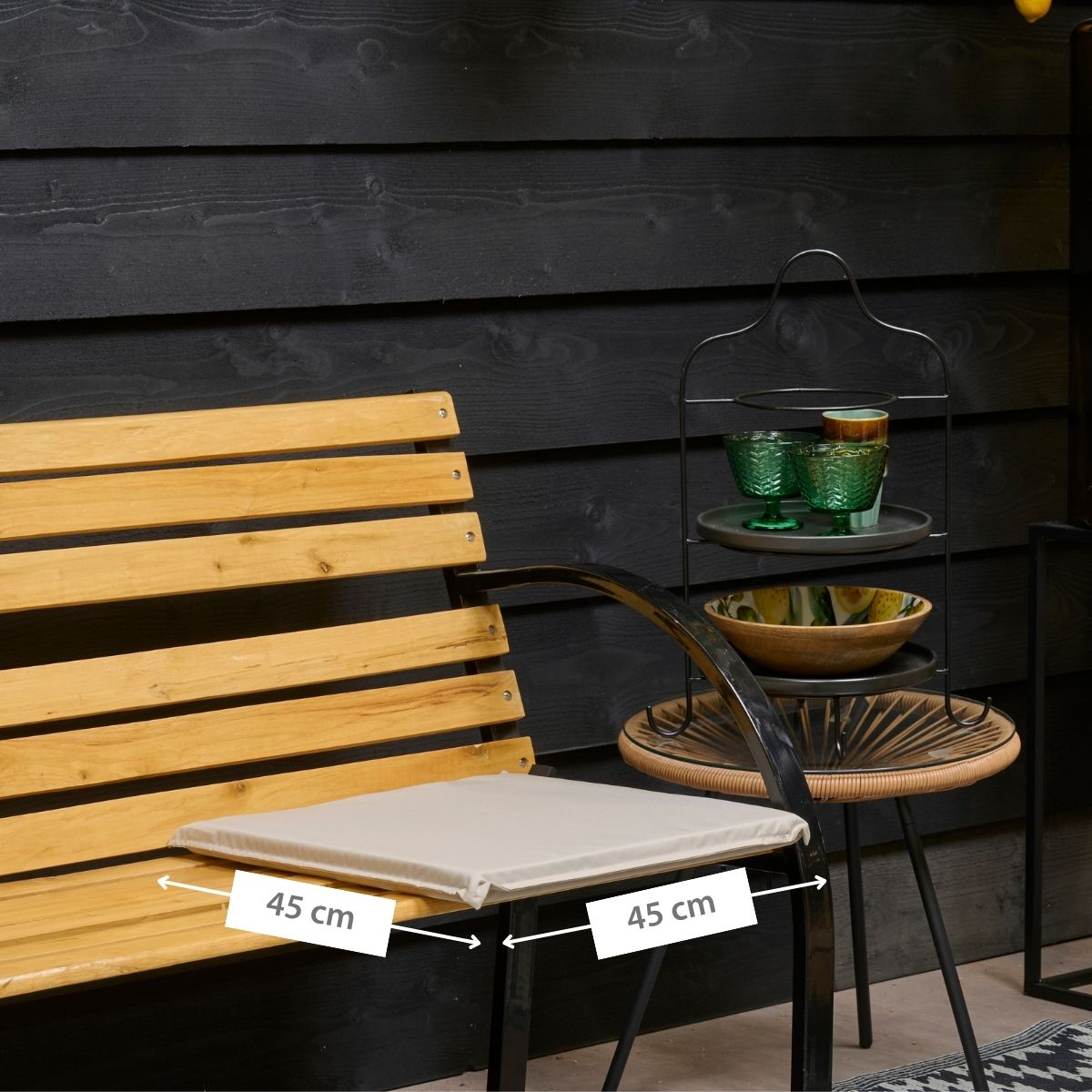 Wooden bench with cushion against dark wood paneling, side table next to it.