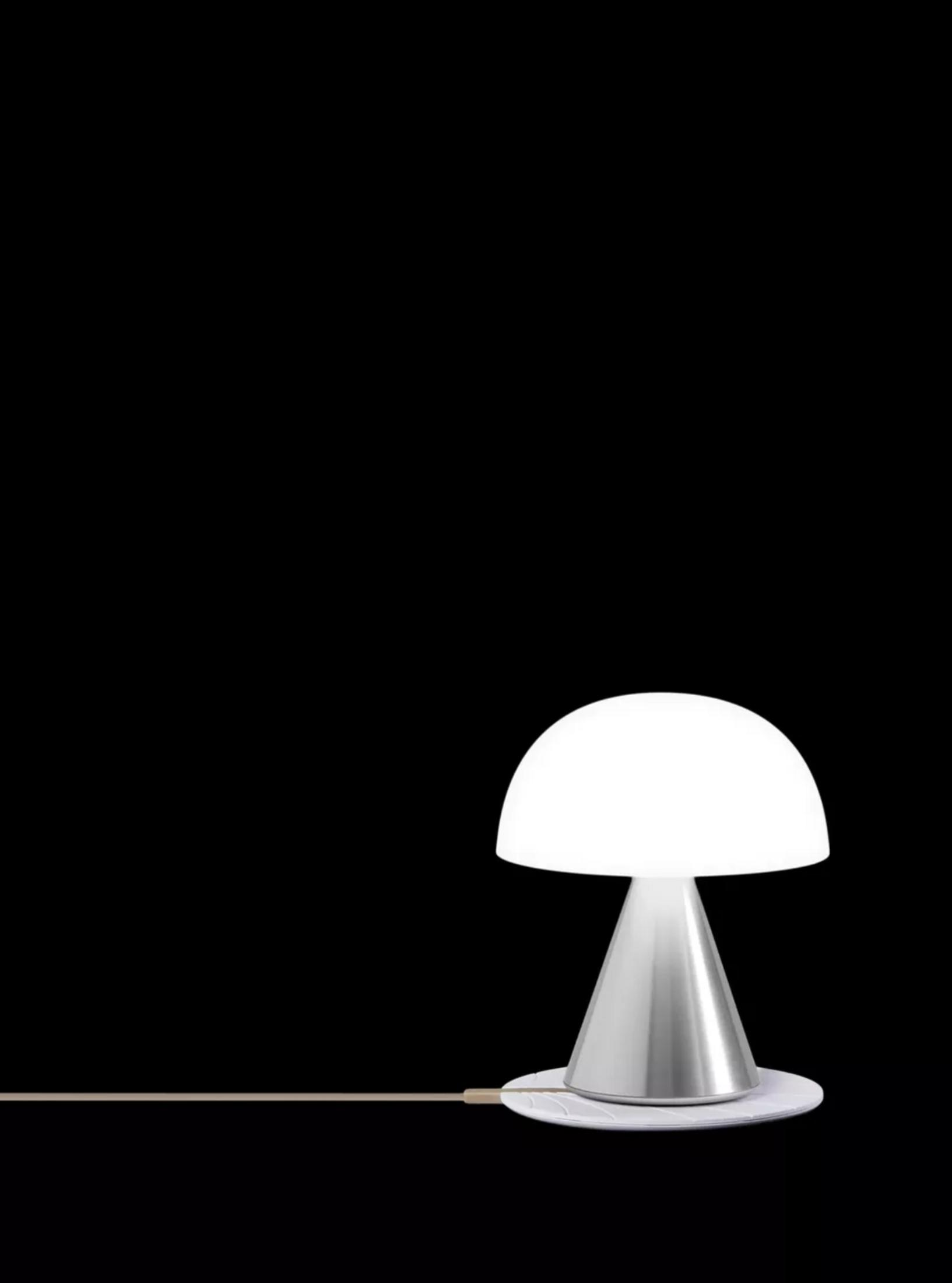Eine weiße Pilzlampe mit silbernem Sockel steht auf einem weißen Untersetzer.