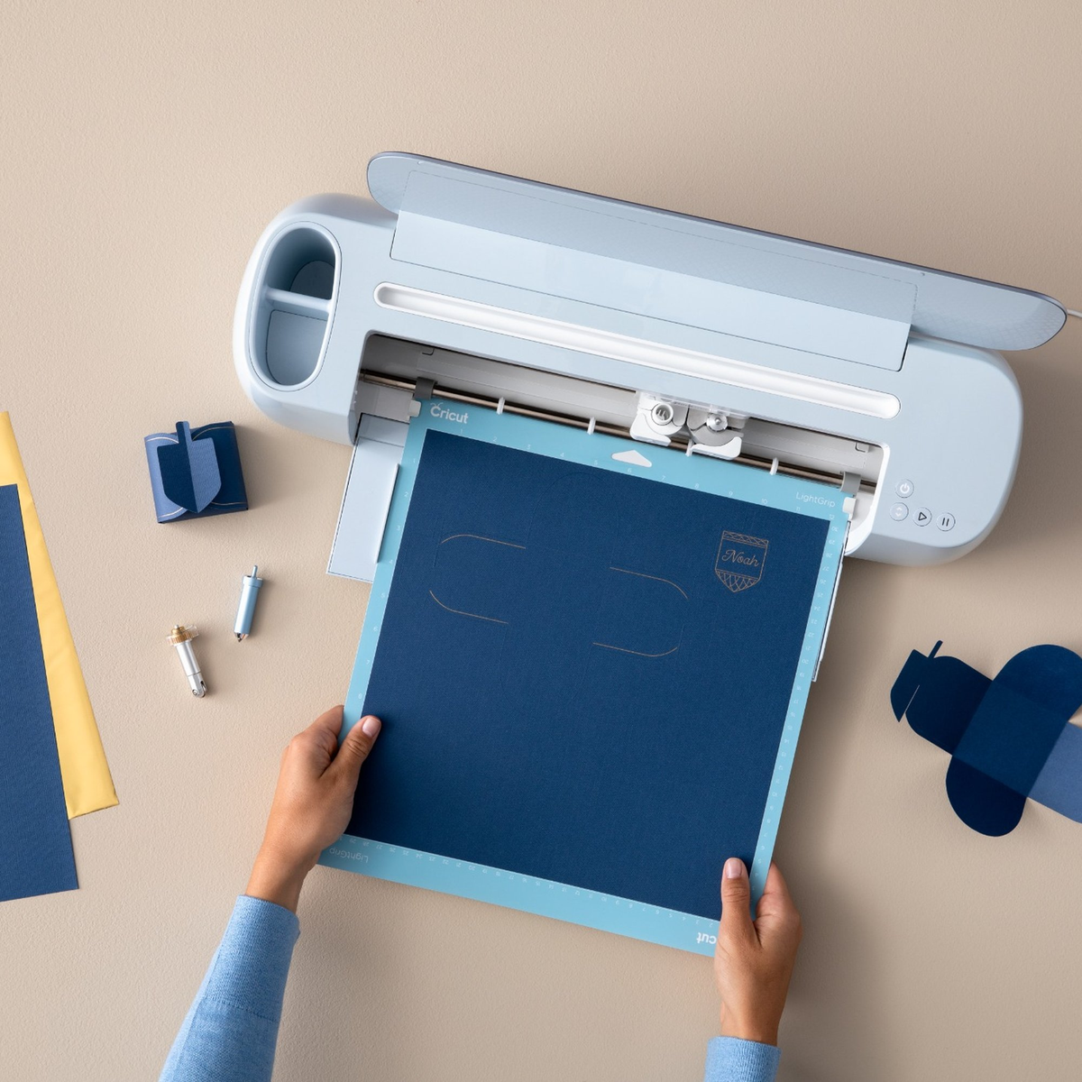 Hände legen eine blaue Matte mit einem Cricut-Schneideplotter ein.
