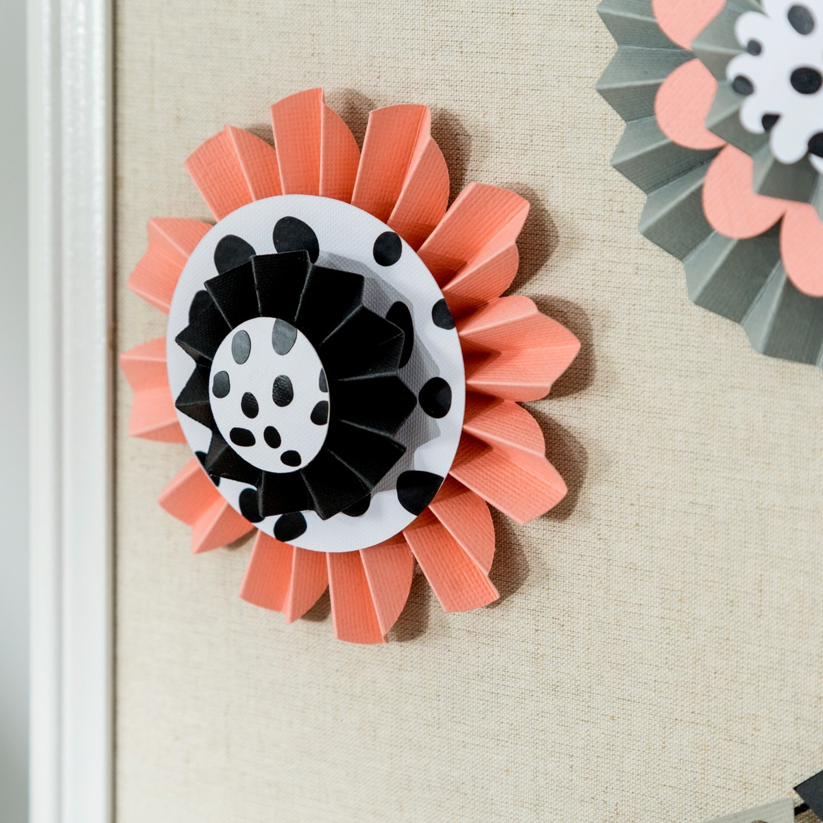 Ein Pfirsichfarbenes Papierornament mit schwarzen Punkten auf weißem Hintergrund.