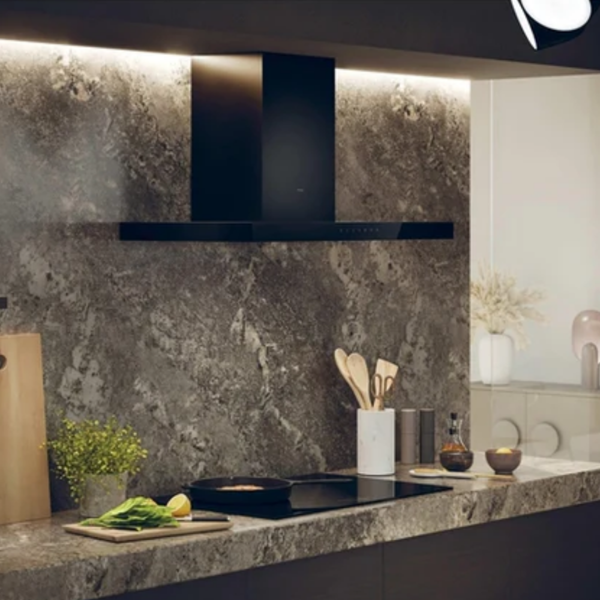 Cocina moderna con salpicadero de piedra oscura, campana extractora y vitrocerámica.