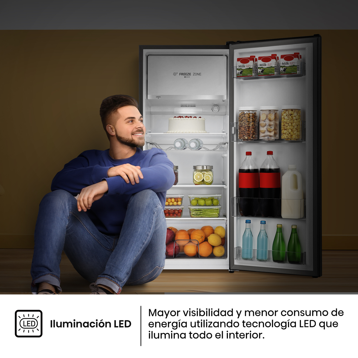Uomo seduto davanti a frigorifero aperto pieno di cibo, illuminato da LED.