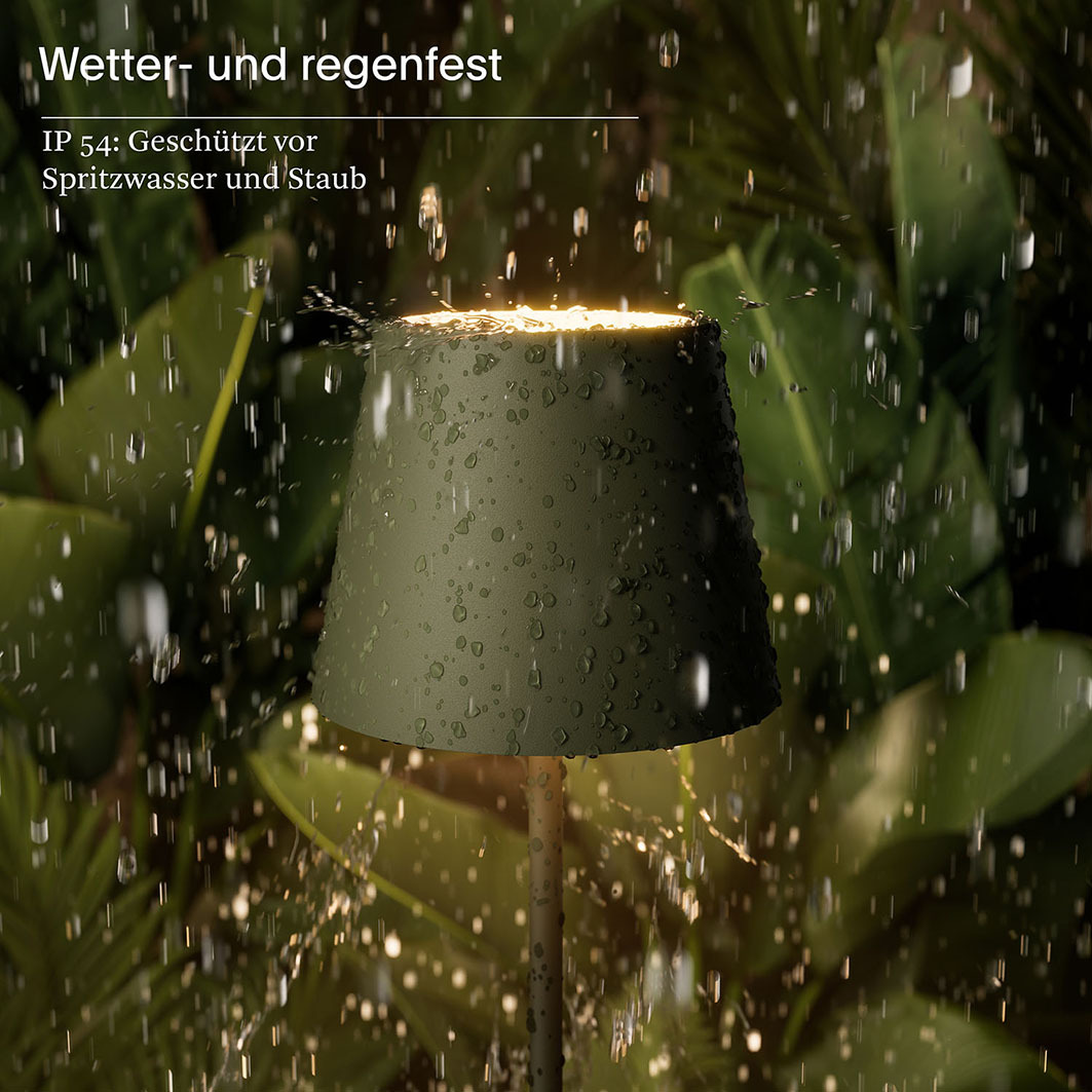 Eine grüne Außenlampe ist im Regen beleuchtet, mit Wassertropfen auf der Oberfläche.