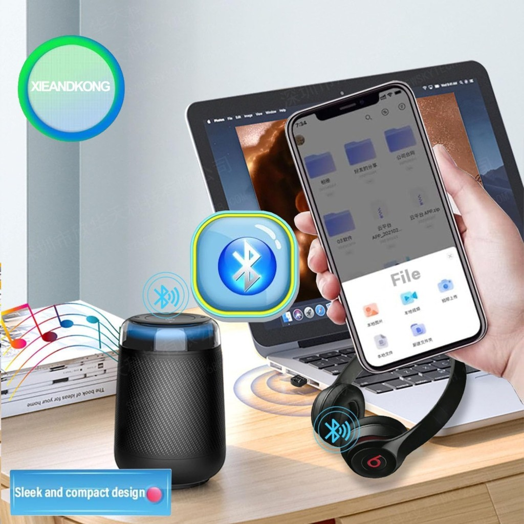 Dizüstü bilgisayarın önünde siyah bir Bluetooth hoparlör, kulaklık ve akıllı telefon.