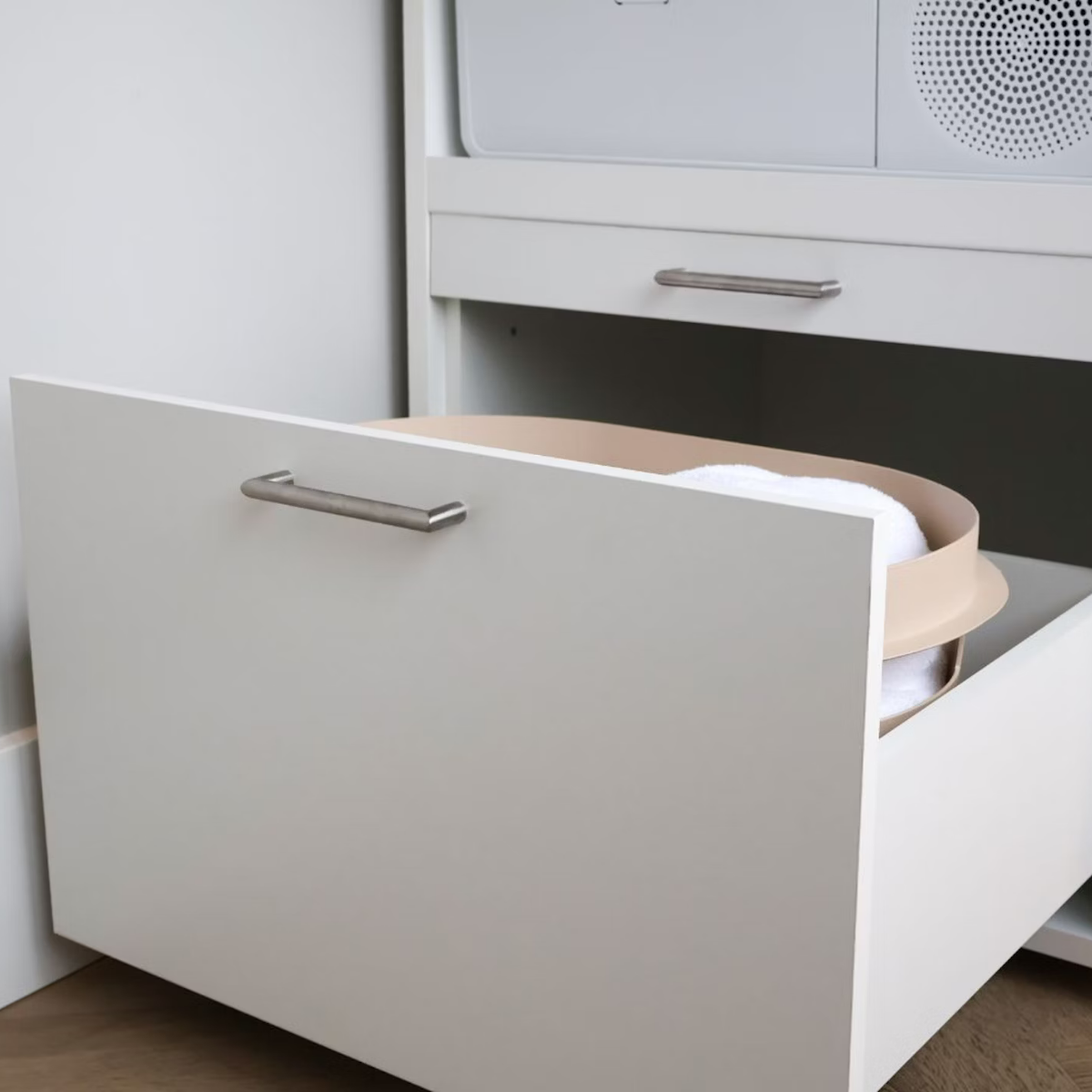 Eine offene Schublade mit einem beige Behälter mit weißen Handtüchern darin.