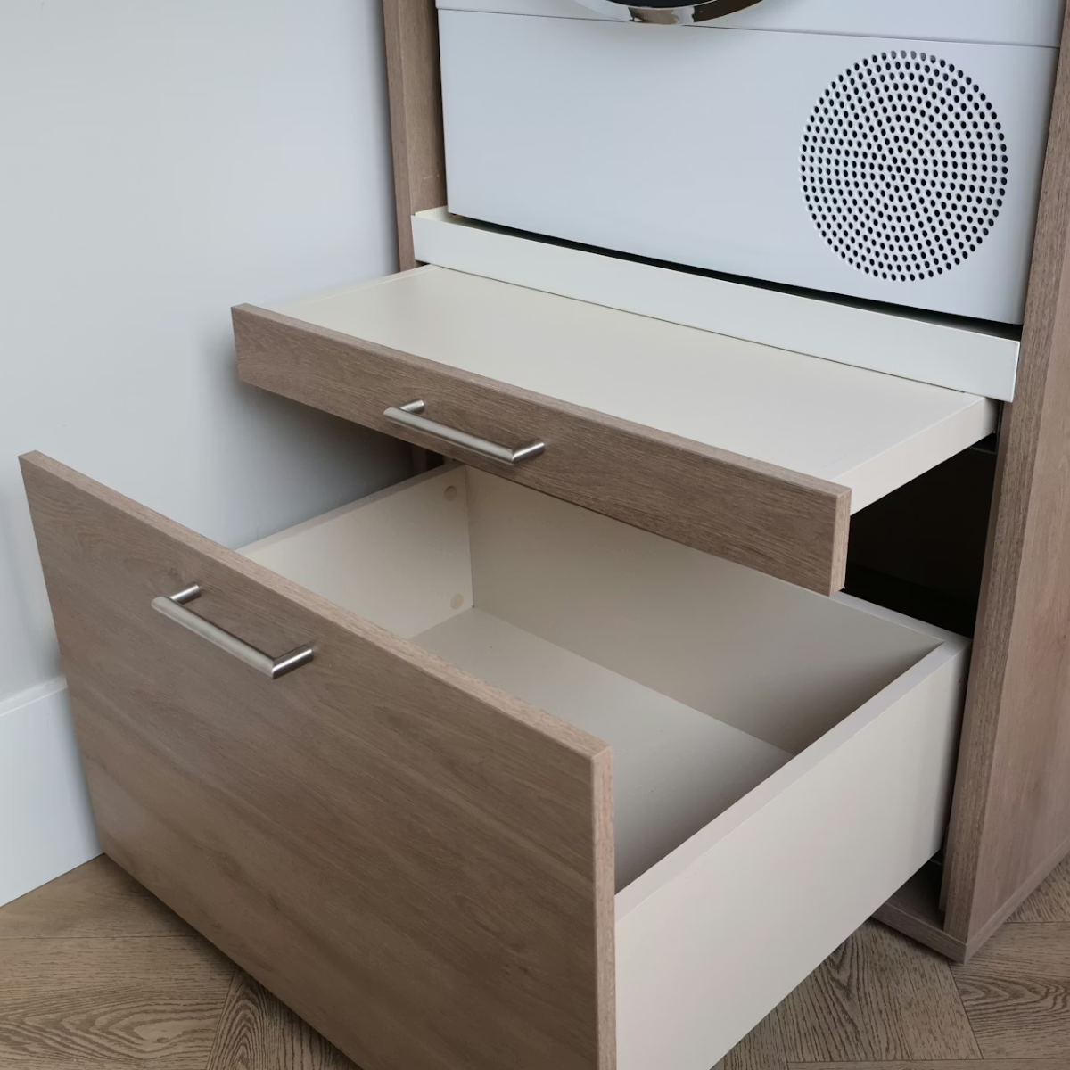 Ein Holzschrank mit zwei offenen Schubladen und einem weißen Gerät darüber.