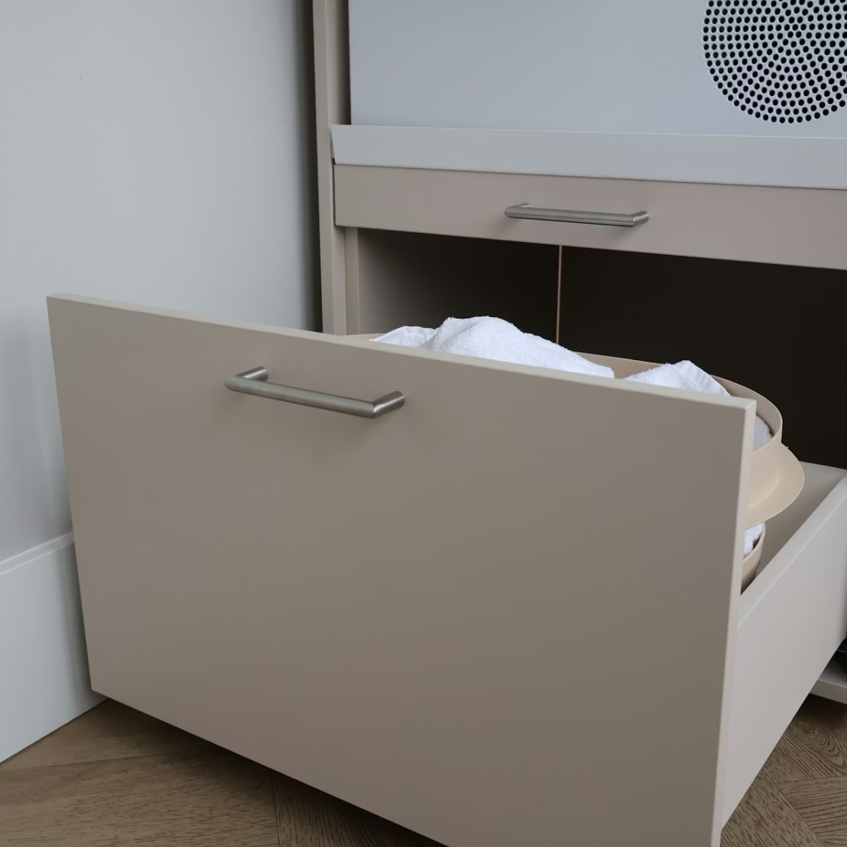 Ein offenes beige Schubladenelement mit weißen Handtüchern gefüllt.