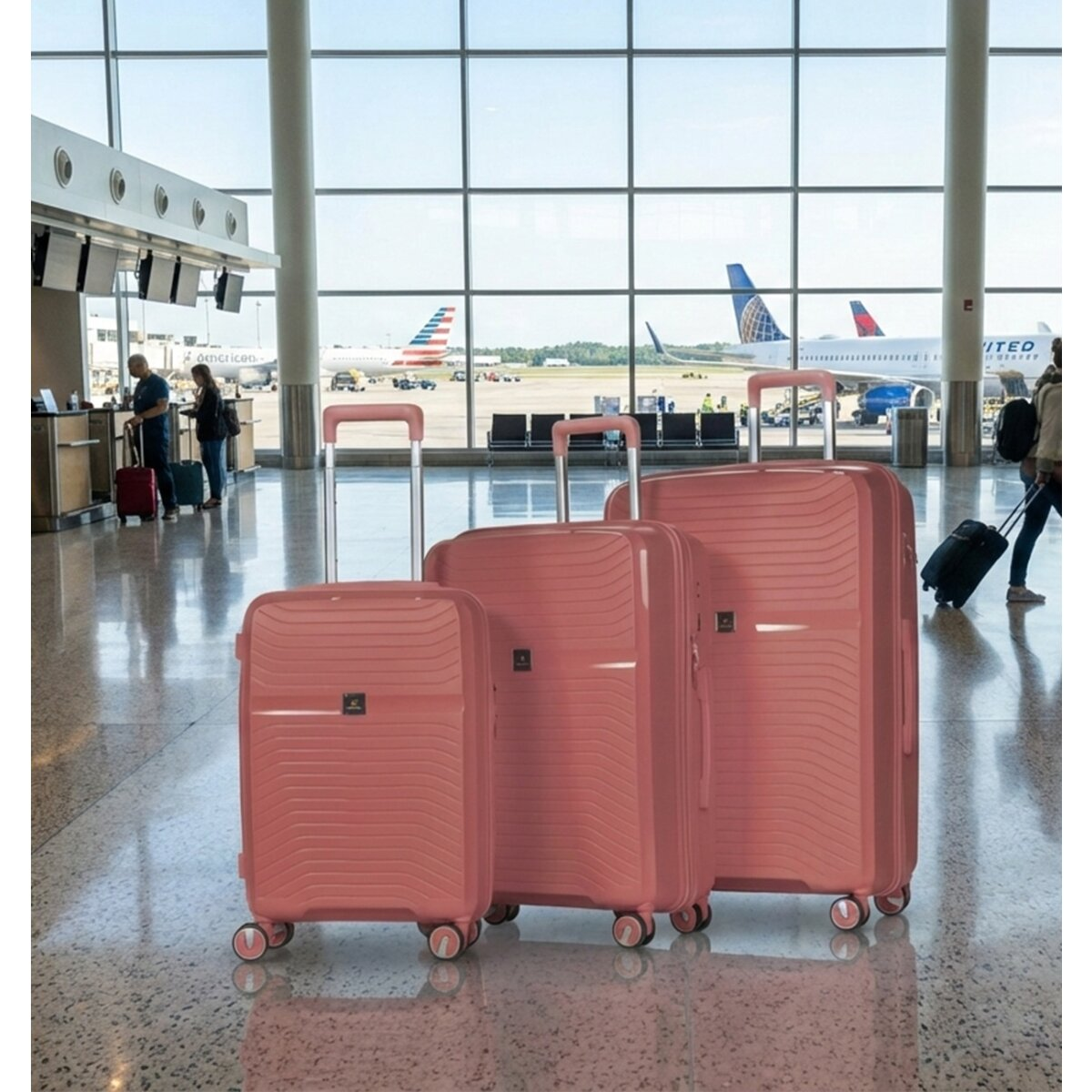 Drei rosafarbene Koffer stehen im Flughafen vor einem großen Fenster. Flugzeuge sind draußen zu sehen.