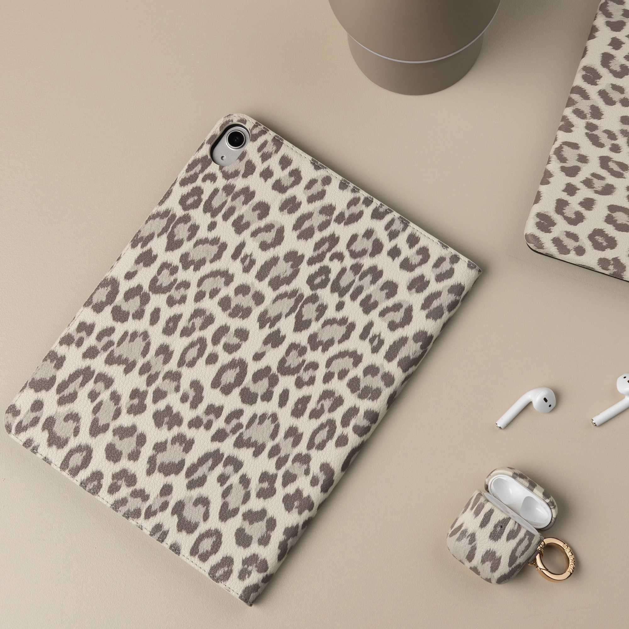 A tablet case, AirPods case, and earbuds with a leopard print.