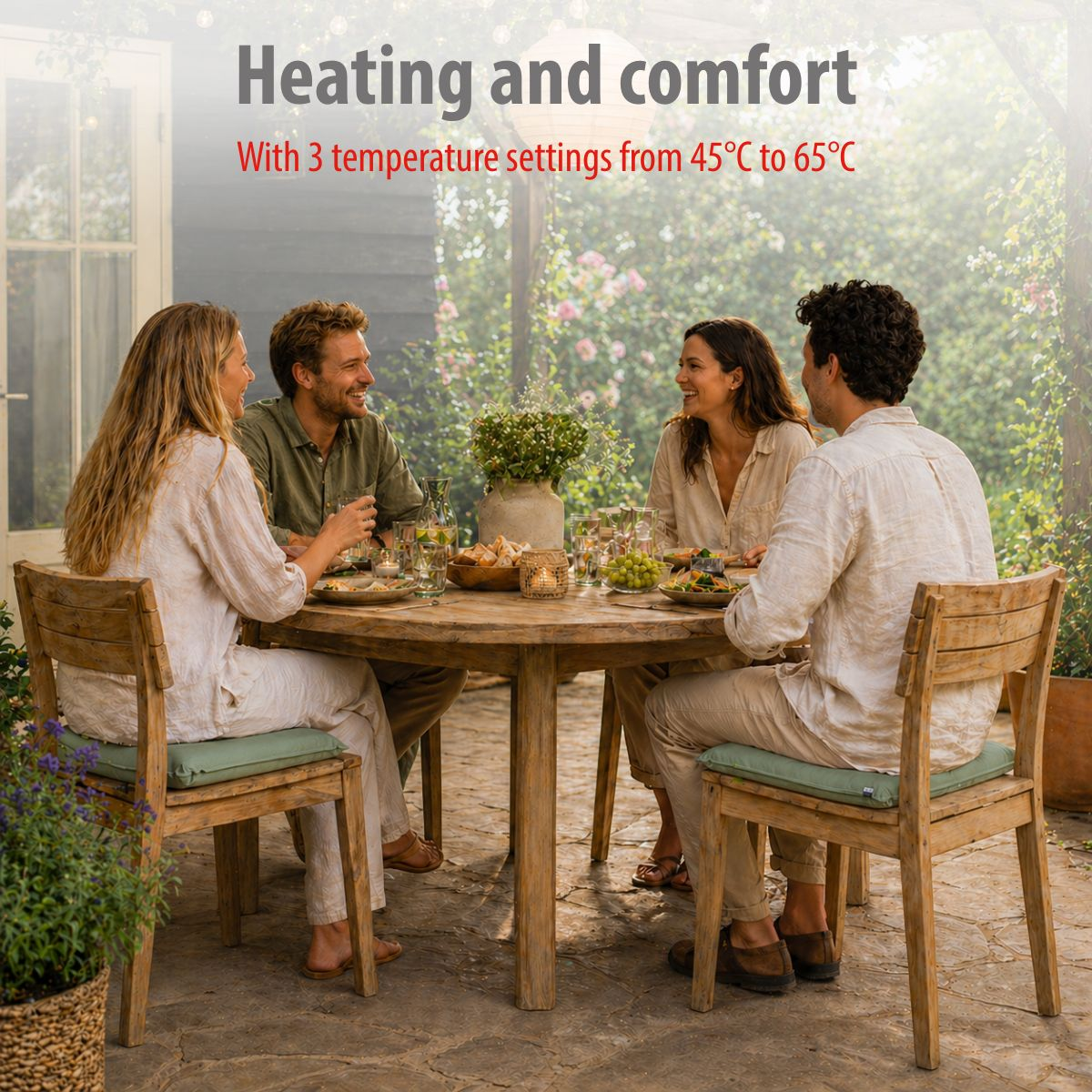 Four people sit at a wooden table outdoors, eating. Plants are in the background.