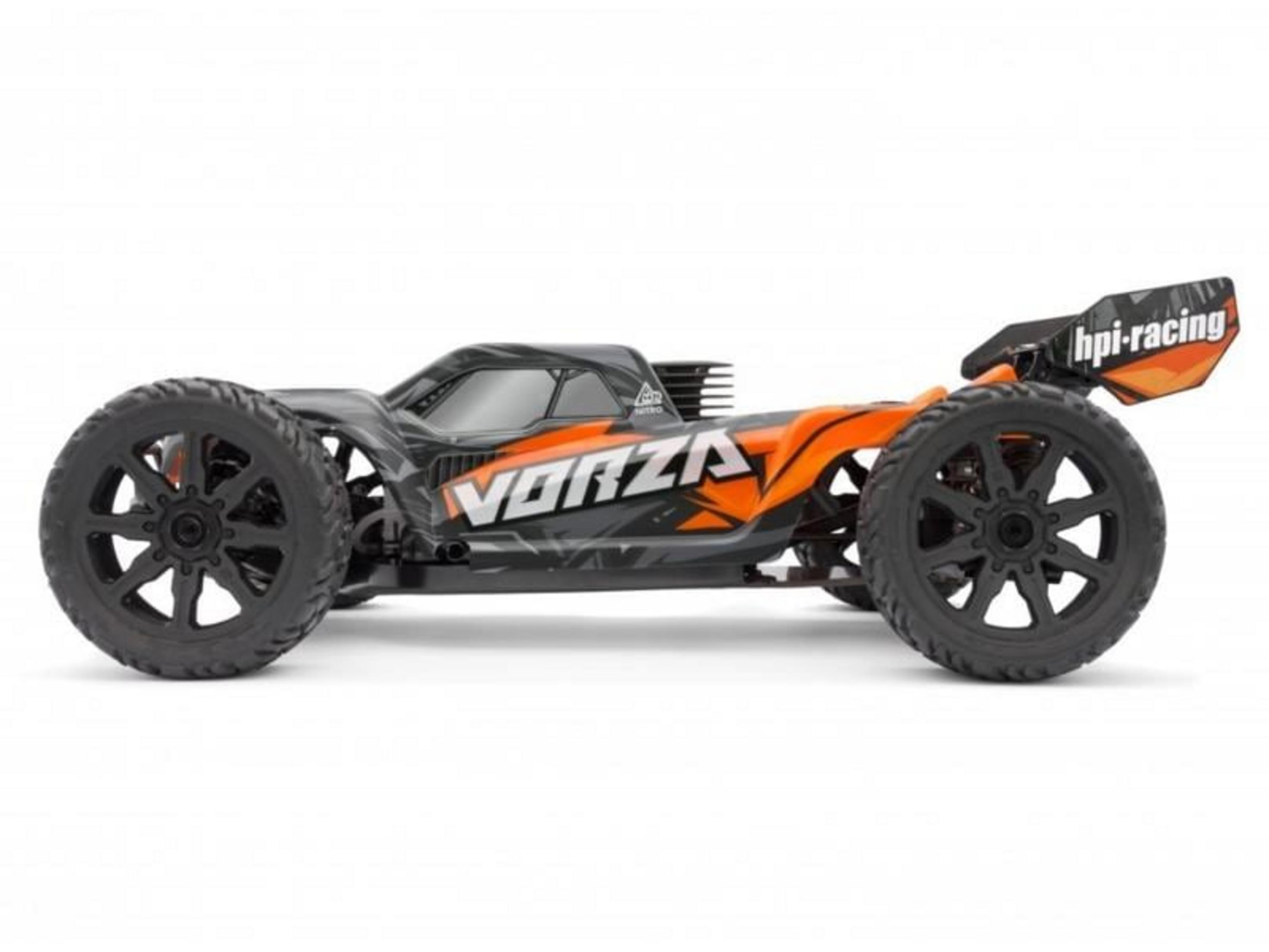 Un buggy a control remoto negro y naranja con neumáticos grandes y alerón trasero.