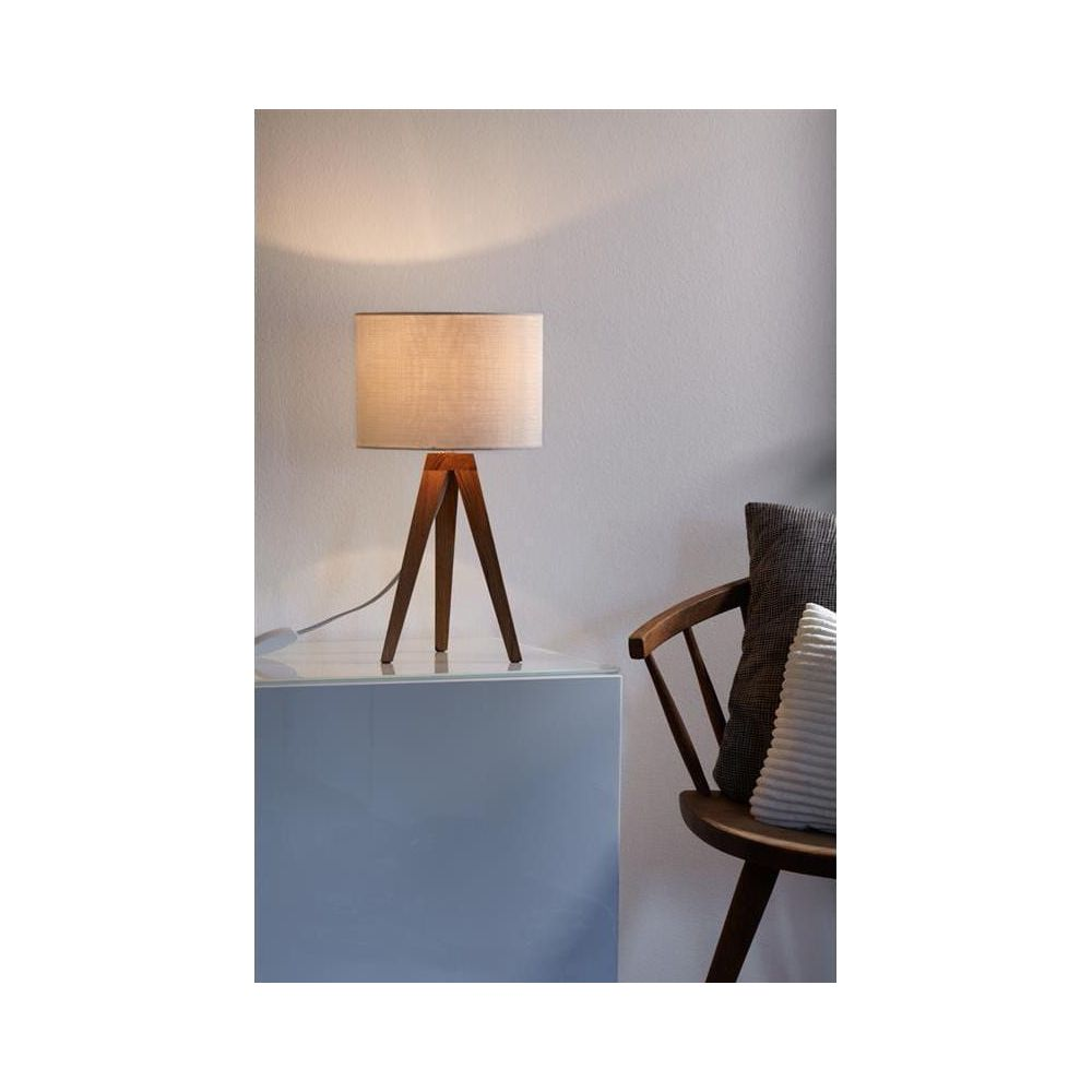 Lampada da tavolo a treppiede in legno con paralume in tessuto su mobile grigio.