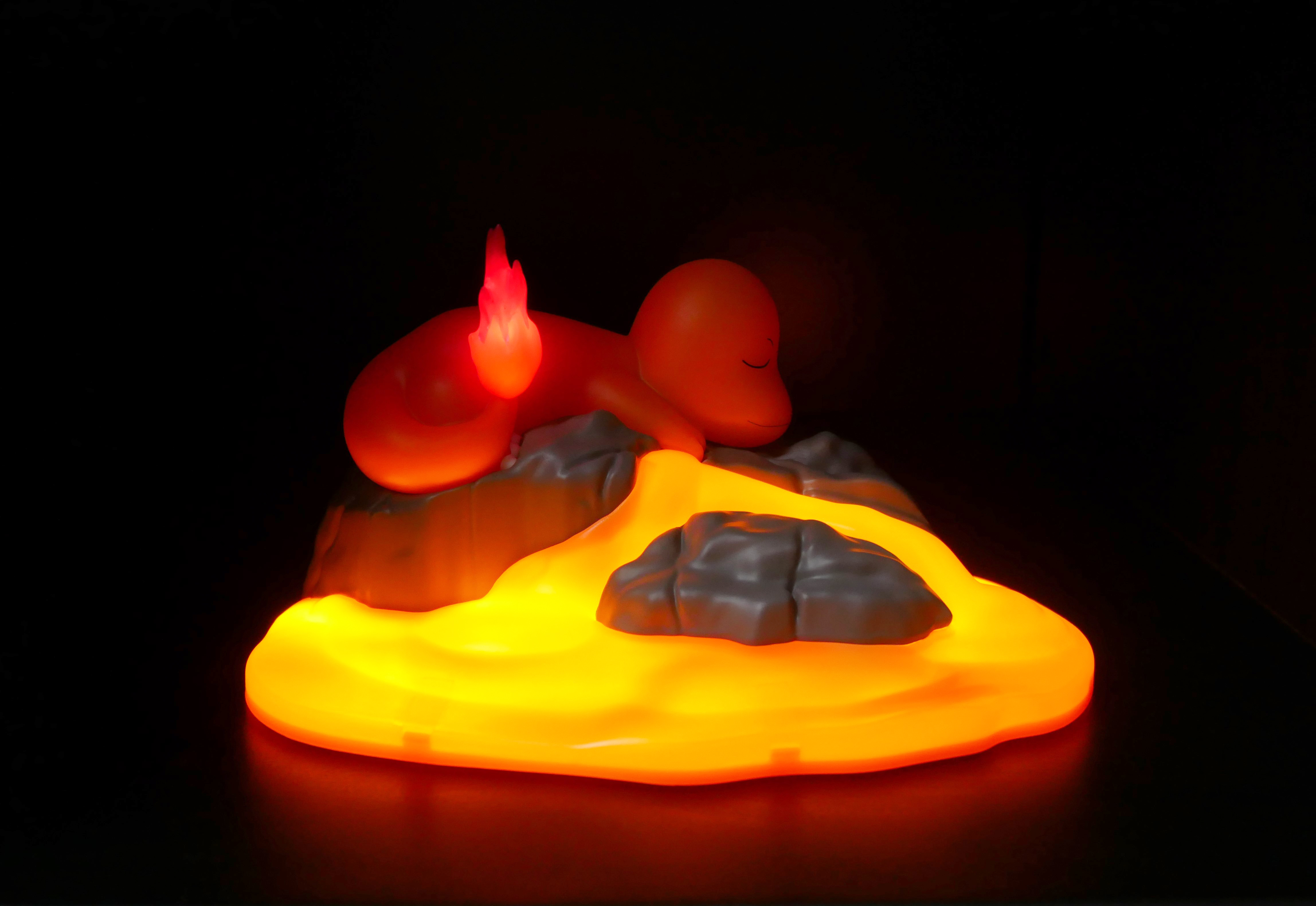 Eine orange Figur mit einer Flamme auf dem Schwanz liegt auf glühenden Felsen.
