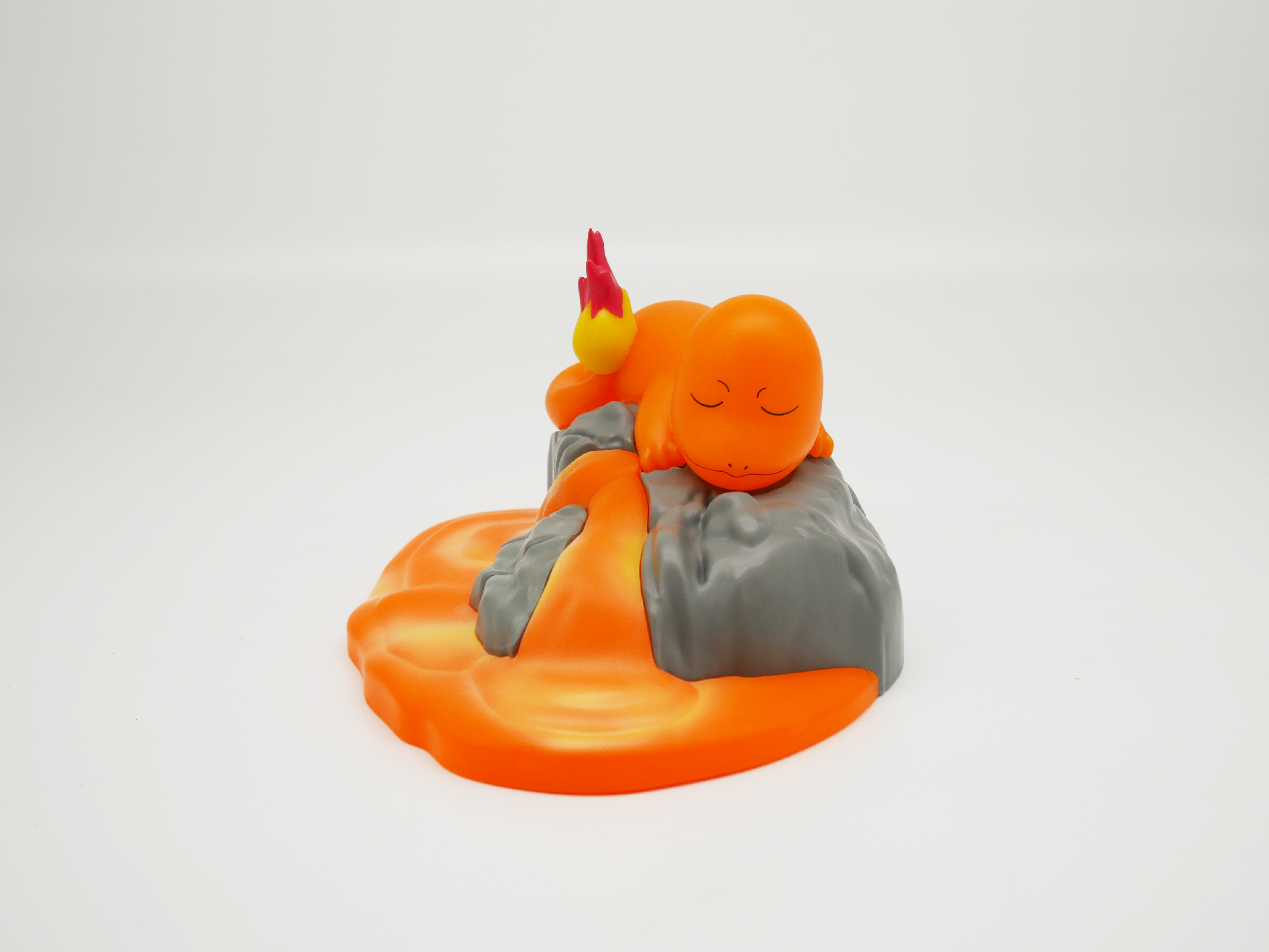 Eine orangefarbene Figur mit geschlossenen Augen schläft auf einem grauen Felsen.