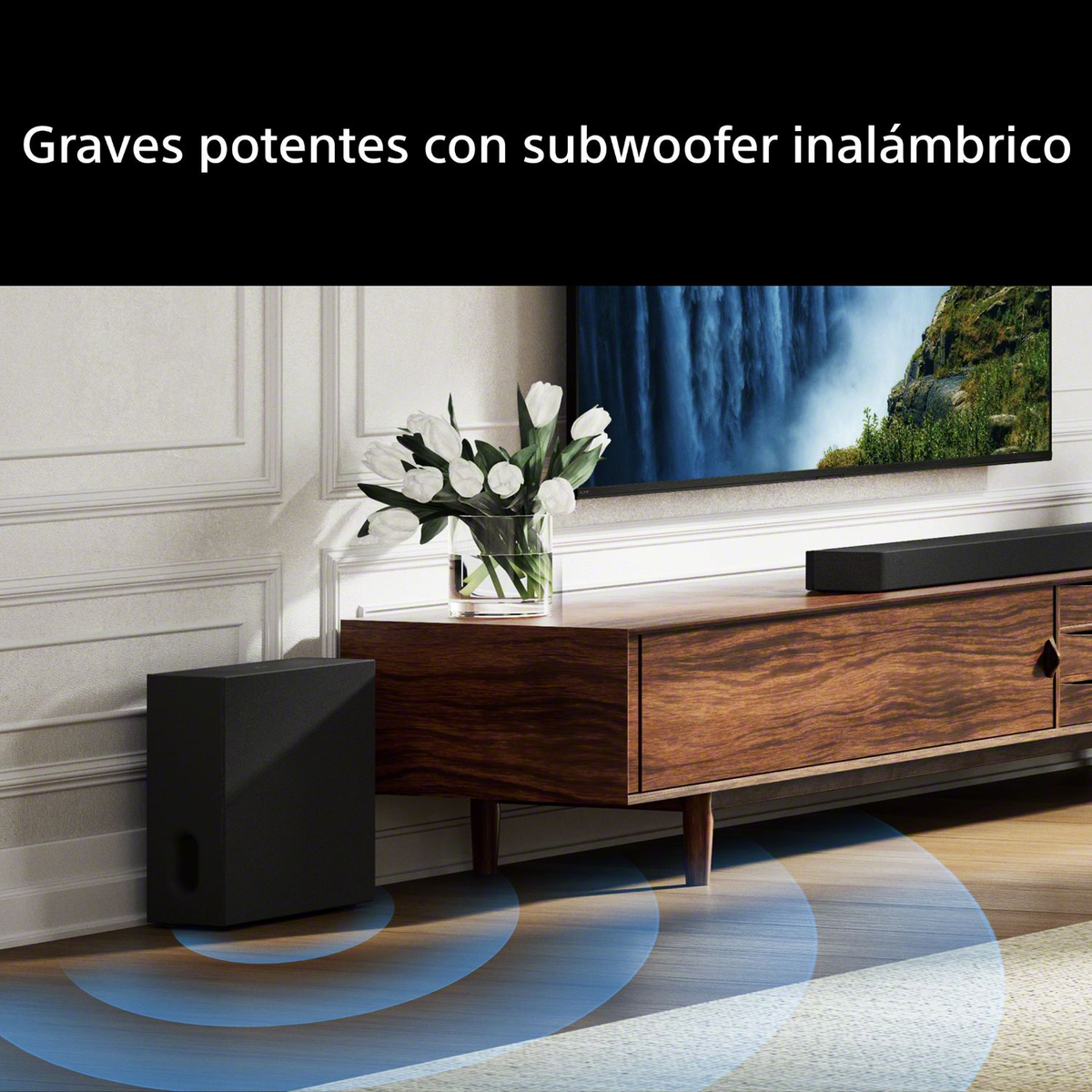 Subwoofer nero a sinistra, console in legno con soundbar, fiori e TV.
