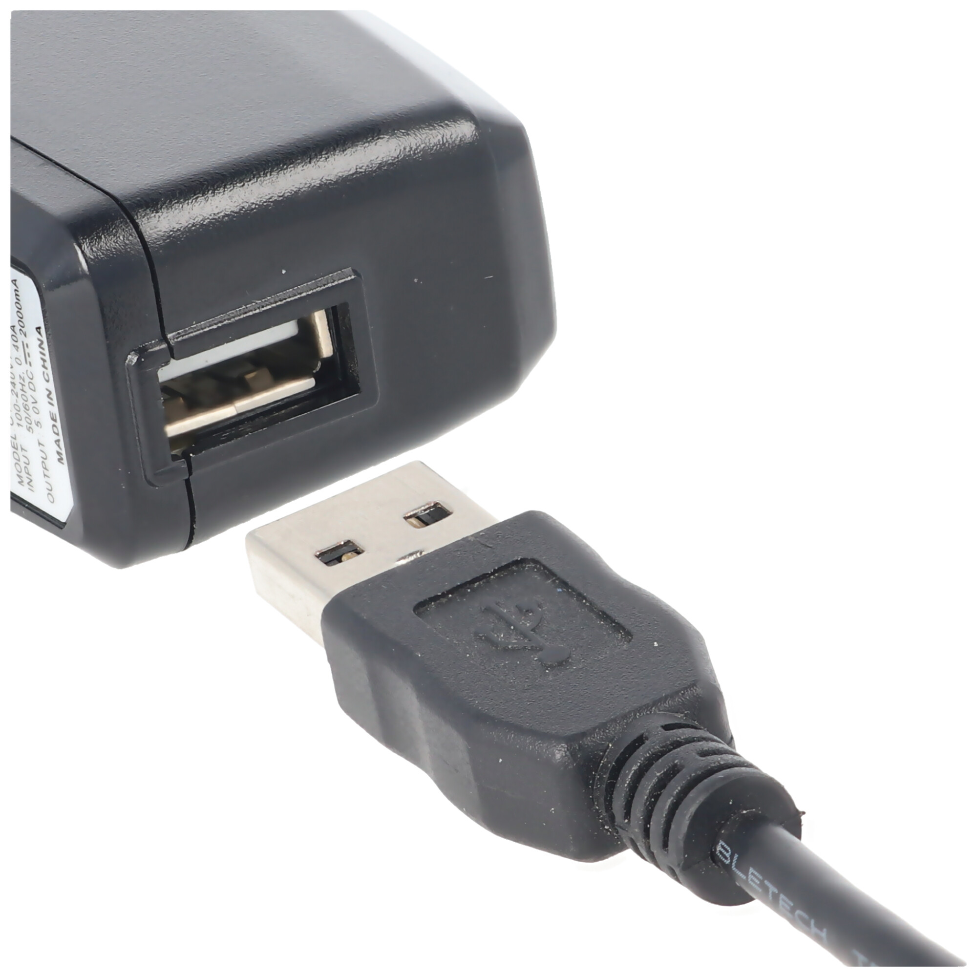 Ein schwarzer USB-Stecker wird in ein schwarzes Netzteil gesteckt.