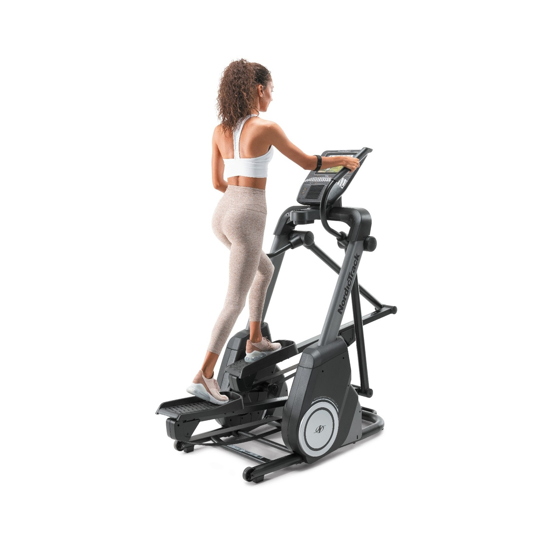 Frau auf einem Heimtrainer mit NordicTrack-Logo, trainiert auf weißem Hintergrund.