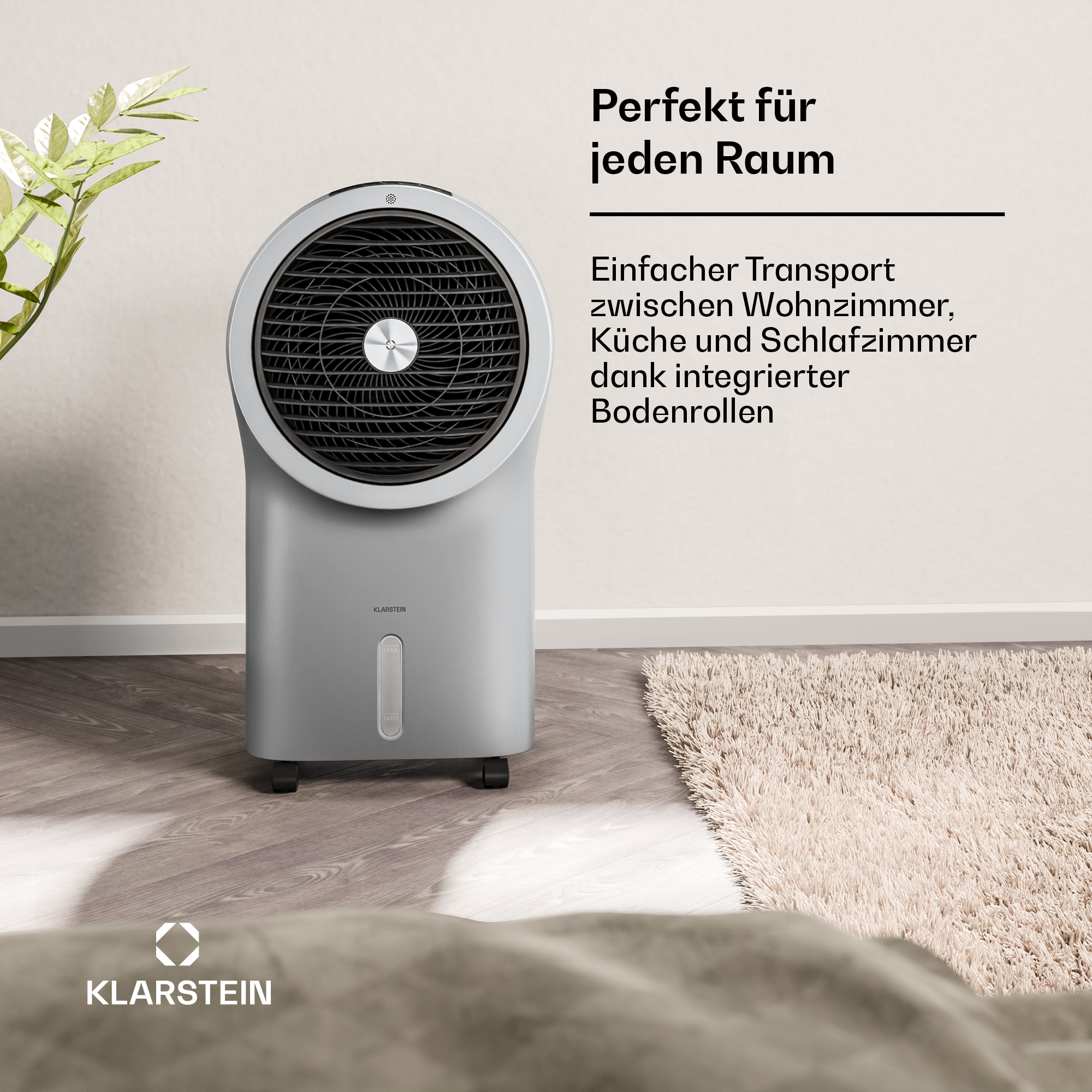 Ein silberner Luftkühler mit Lüftergitter steht auf einem Holzboden neben einer Pflanze.
