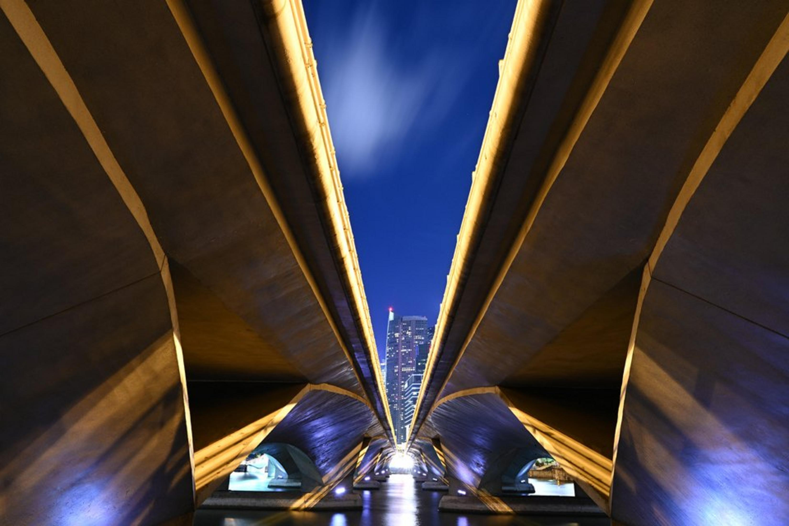 Ponte moderno di notte con nuvole e grattacieli sullo sfondo.