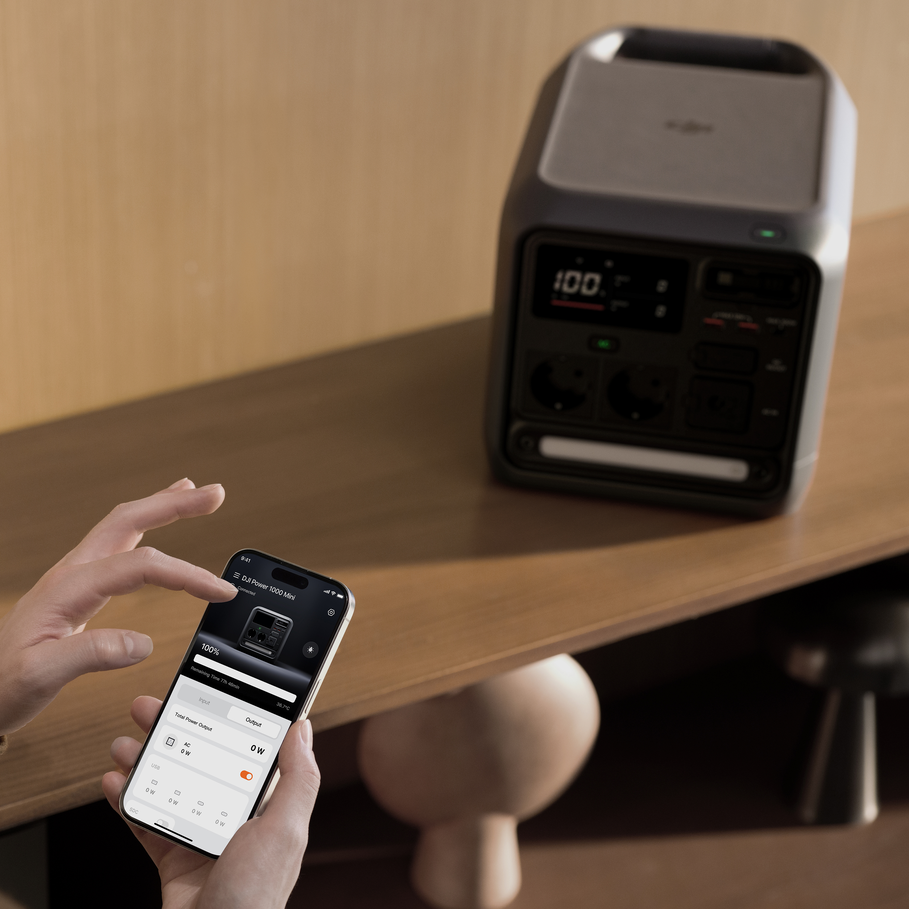 Ein Smartphone zeigt die DJI Power App mit 100% Ladung. Im Hintergrund steht ein Power-Gerät.
