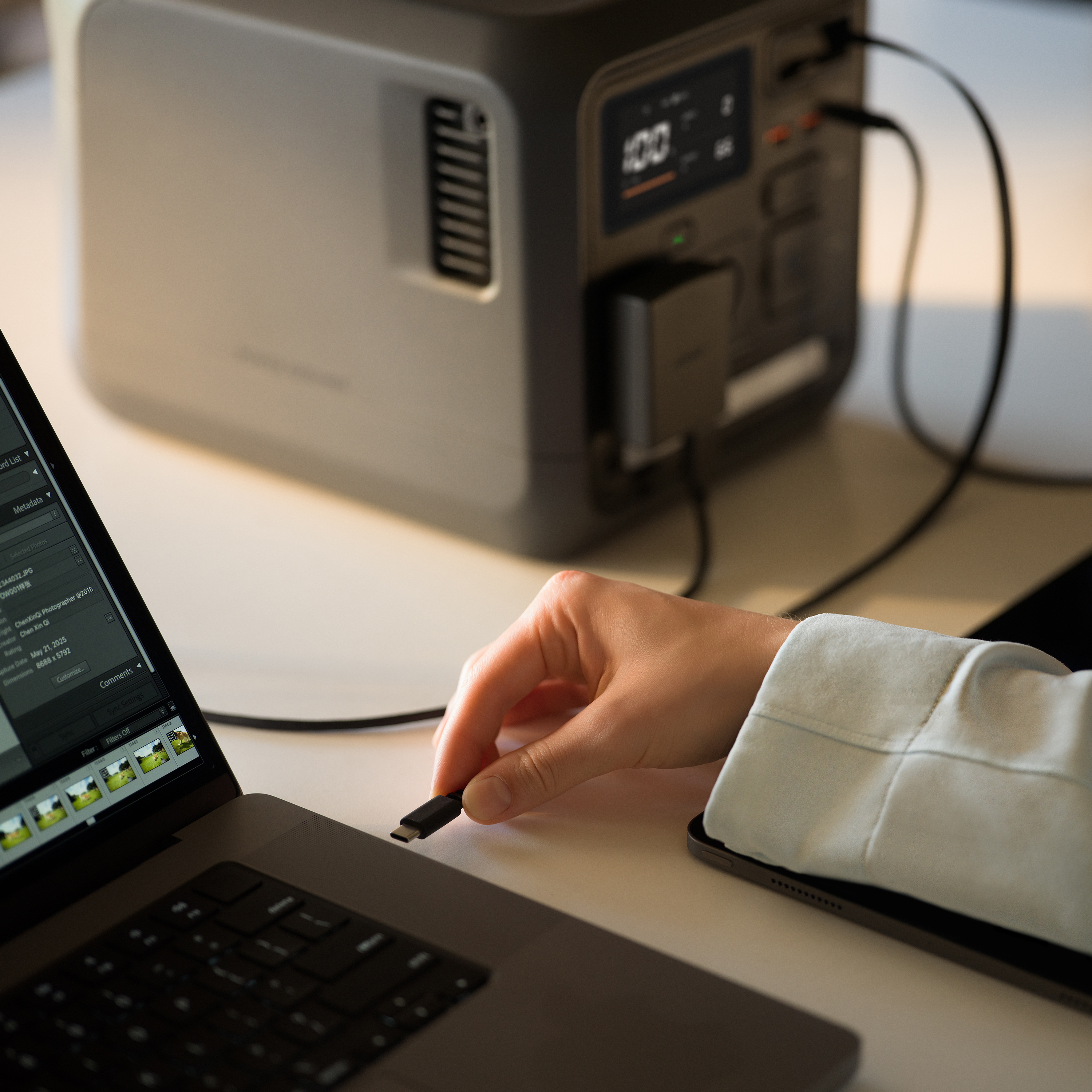 Eine Hand steckt ein USB-C-Kabel in ein Netzteil neben einem Laptop.
