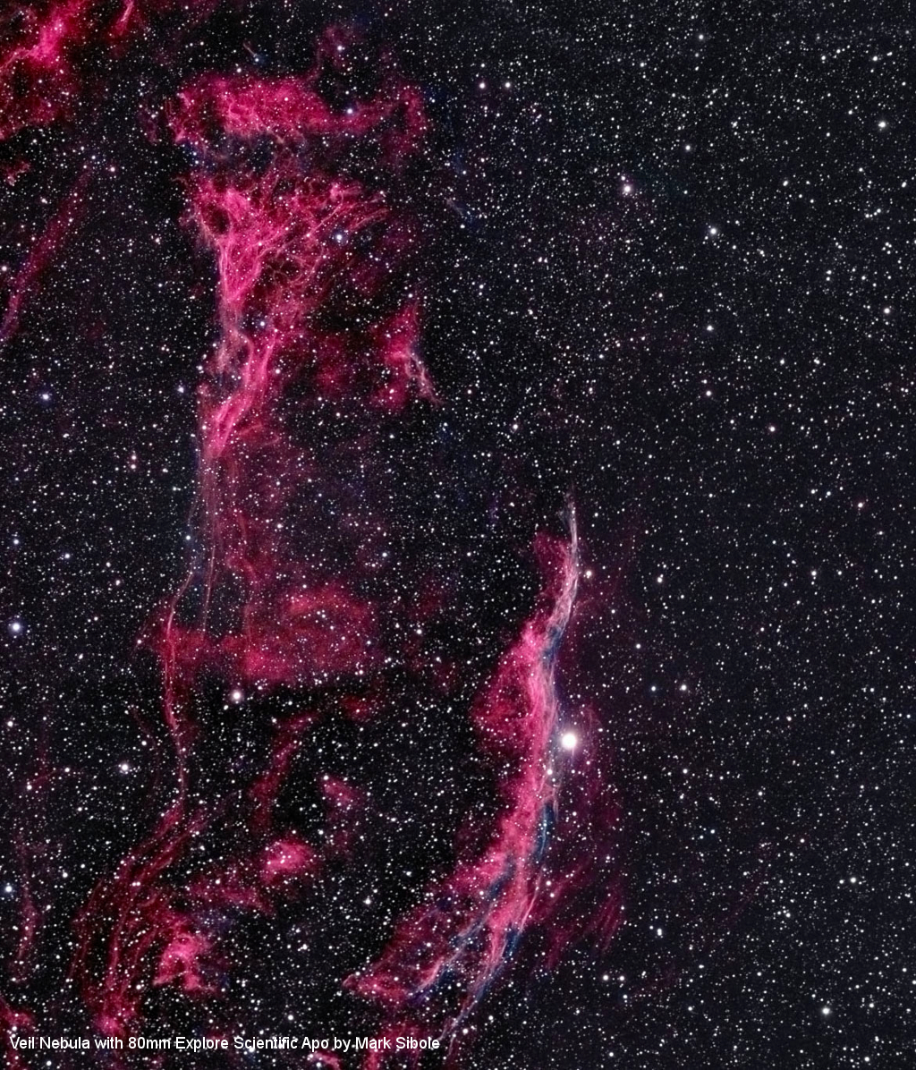La Nebulosa del Velo con nubes de gas rosas y azules contra un cielo nocturno estrellado.