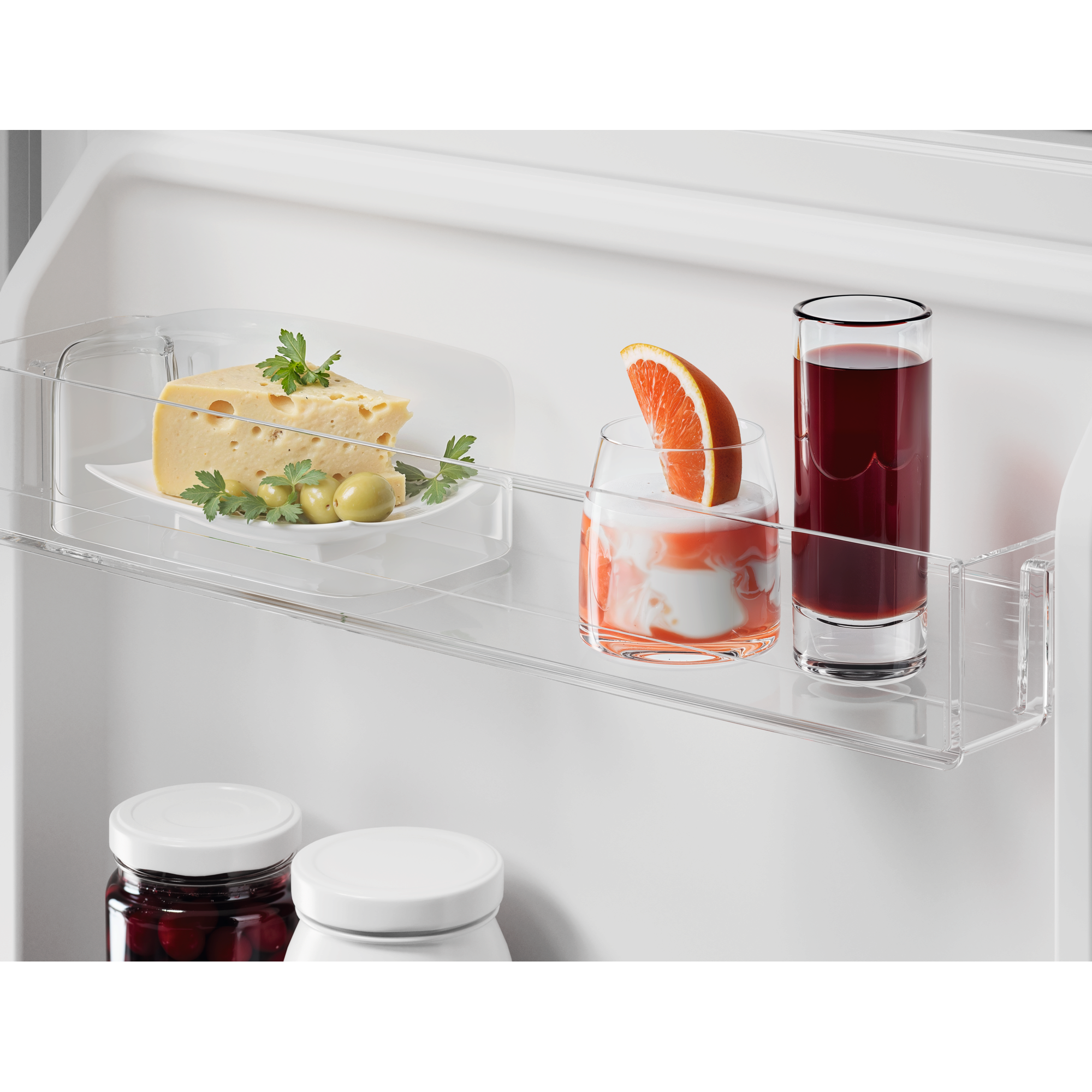 Estante de refrigerador con queso, aceitunas, bebida de pomelo y jugo.