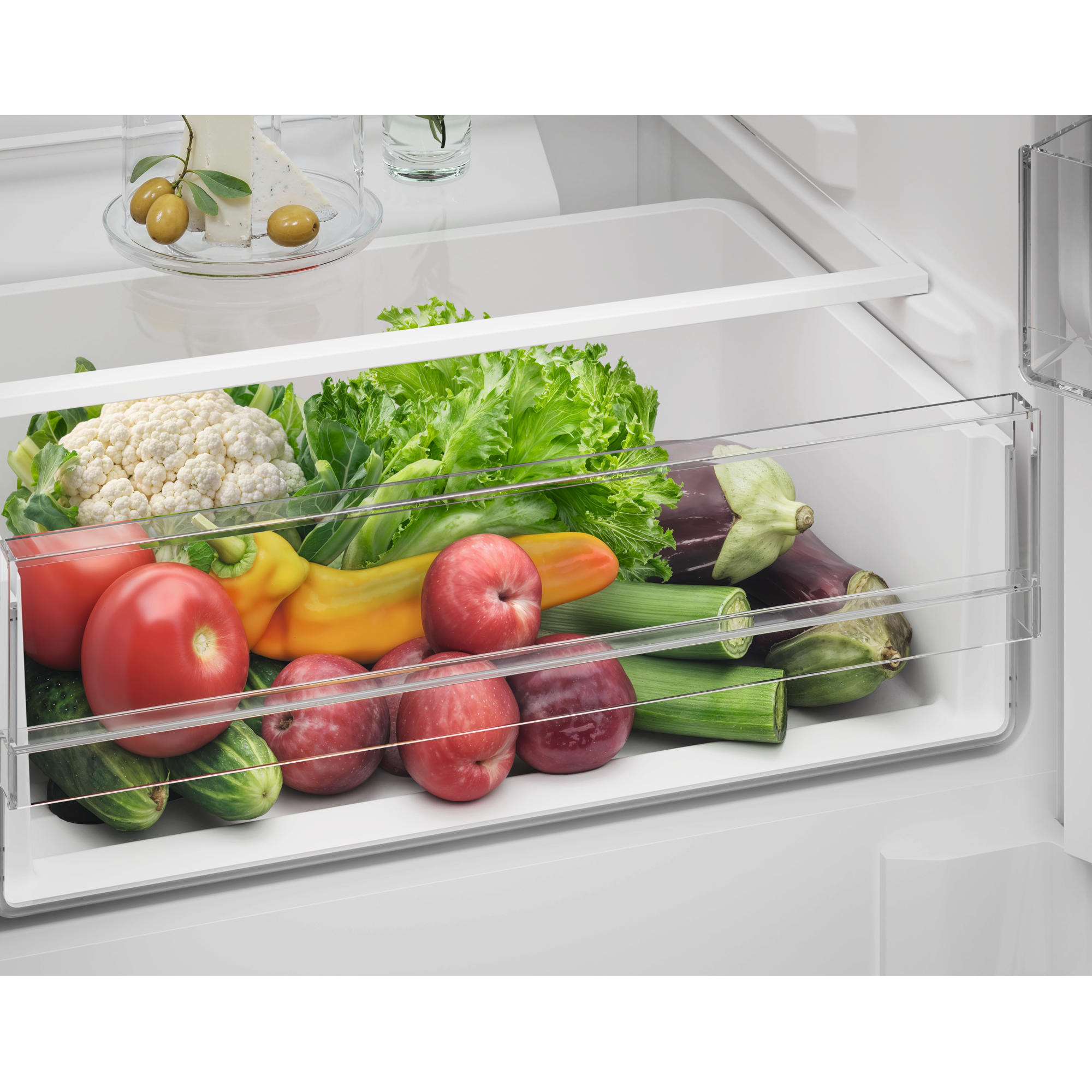 Un cajón de verduras de refrigerador con frutas y verduras frescas como tomates, manzanas y lechuga.