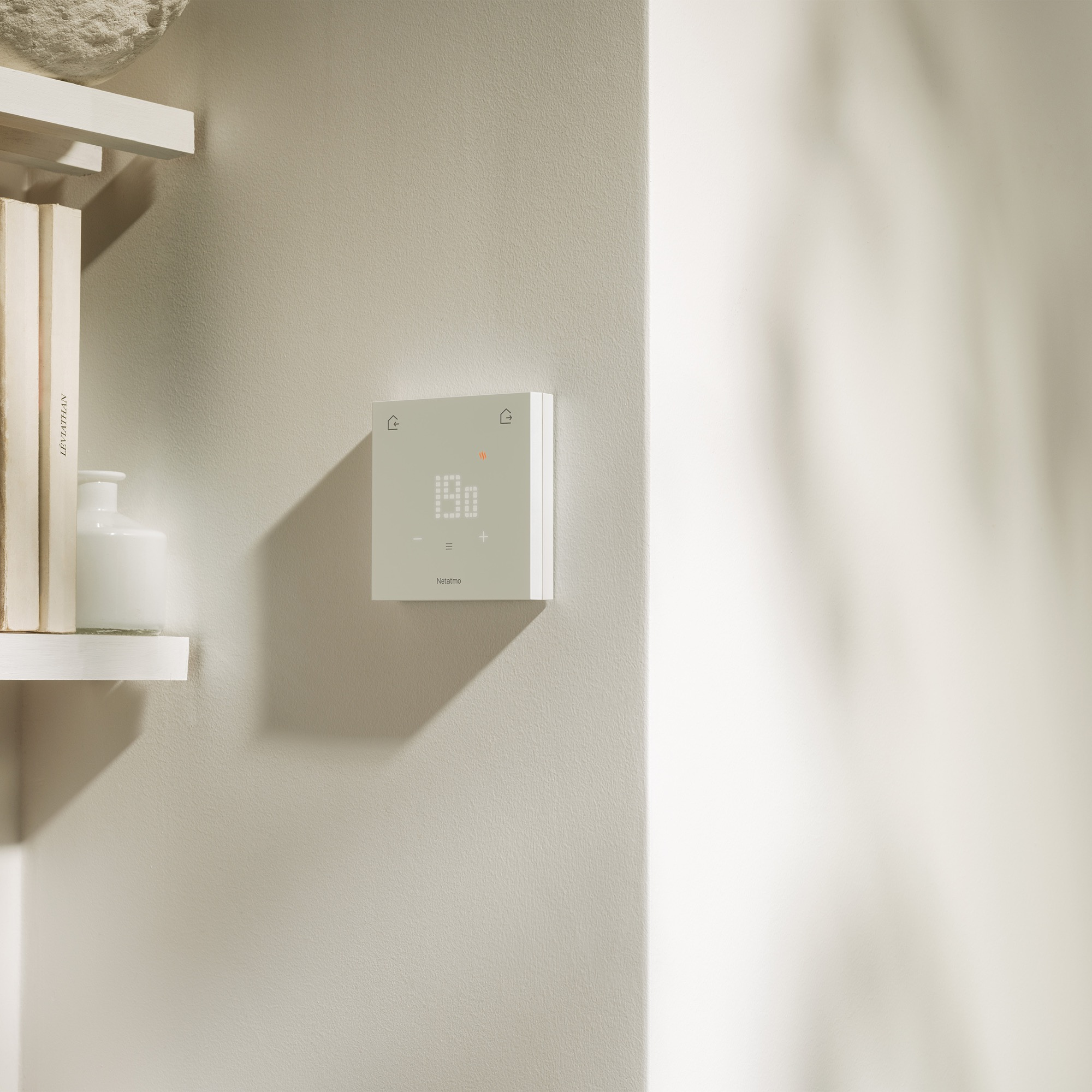 Un thermostat blanc avec un écran numérique sur un mur couleur crème.