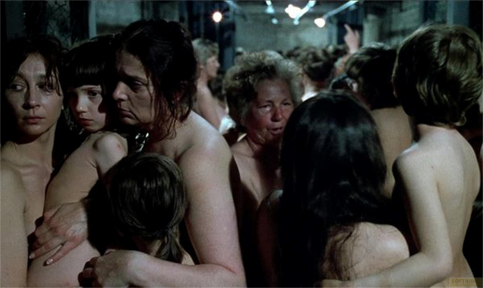 Un gruppo di donne nude sta stretto in una stanza poco illuminata.