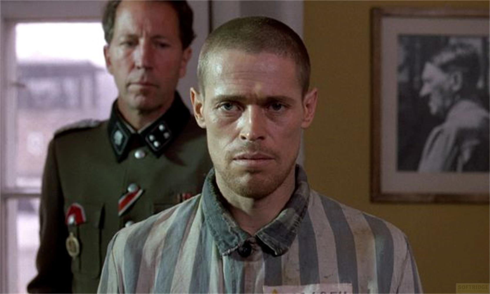 Un uomo in abiti a righe si trova davanti a un uomo in uniforme con un quadro di Hitler.