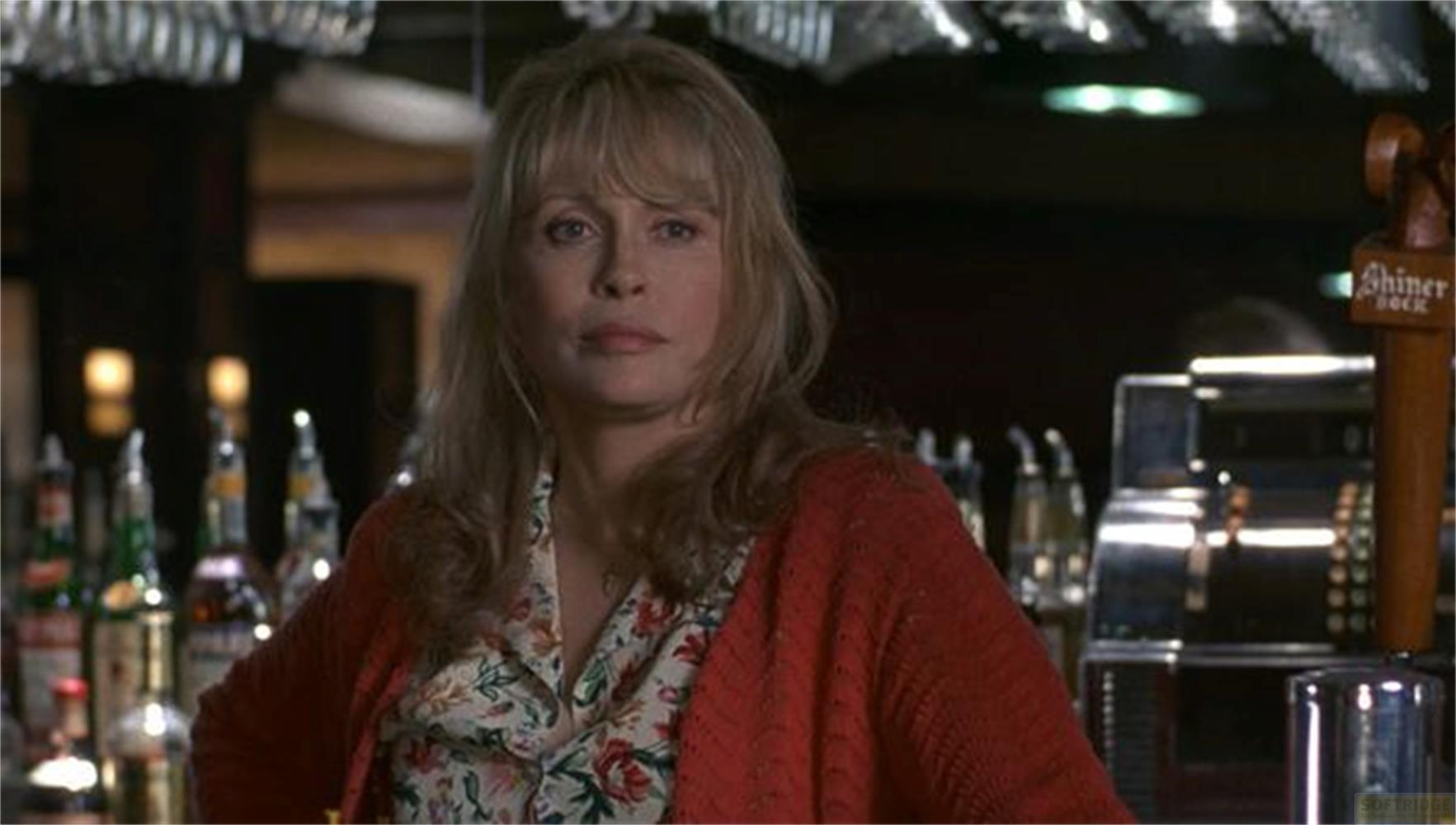 Una donna bionda indossa un cardigan rosso sopra una camicia floreale.