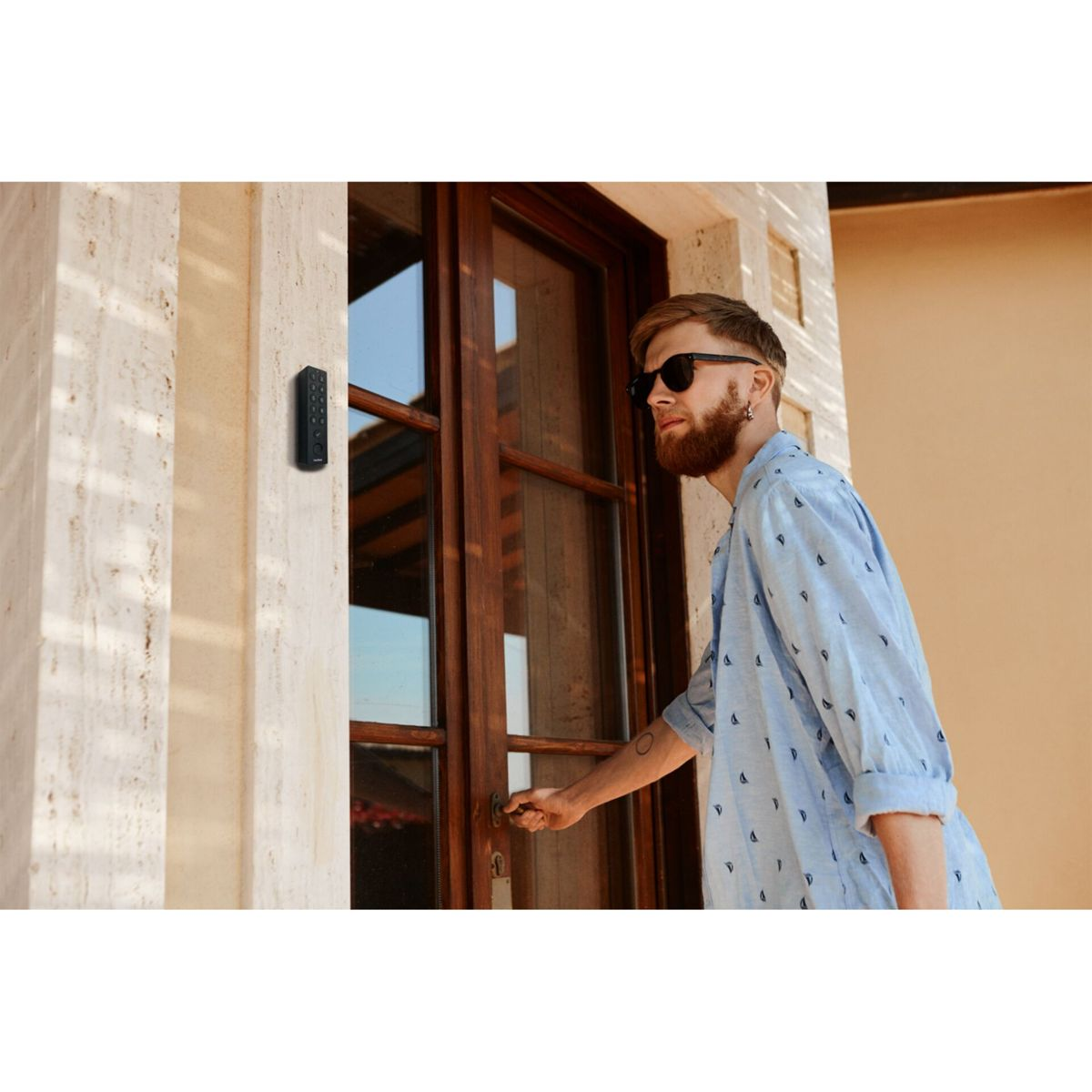 Hombre con barba y gafas de sol abre puerta de madera.