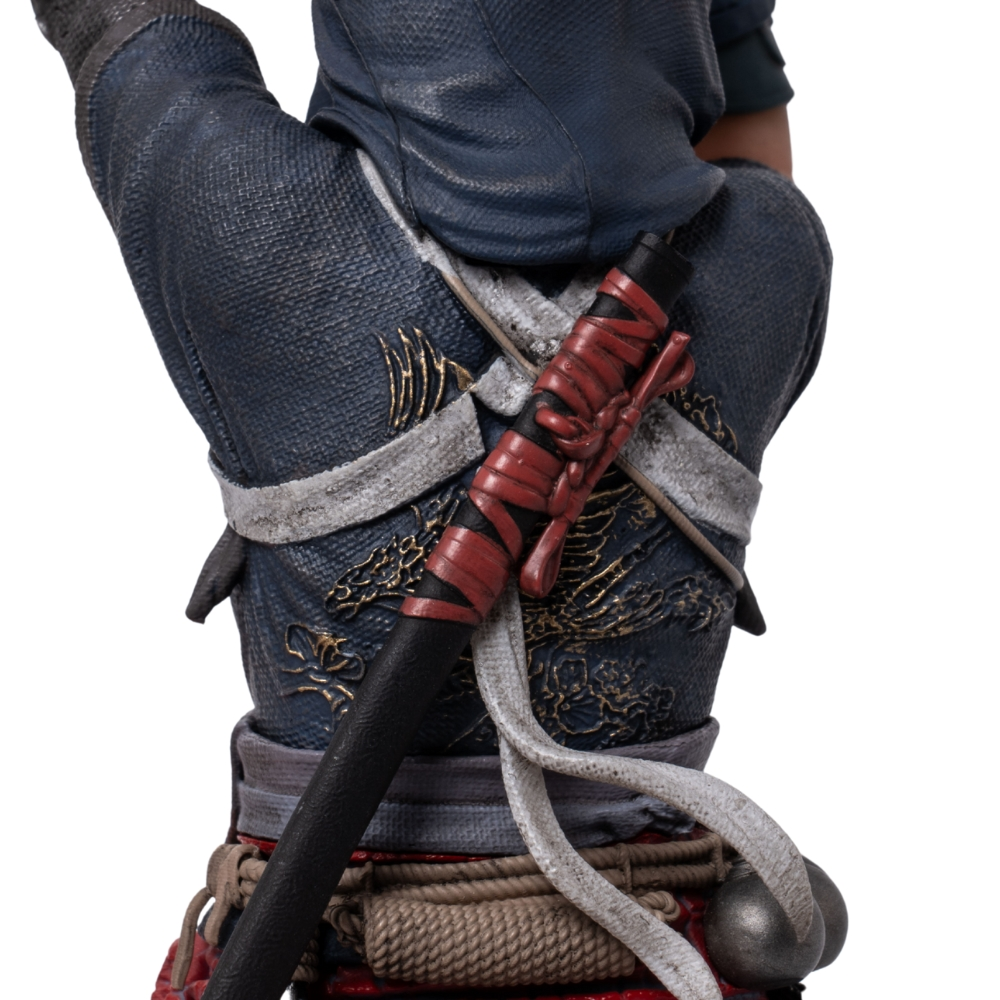 Nahaufnahme einer Figur in blauer Kleidung mit roten Bändern und einem Schwertgriff.