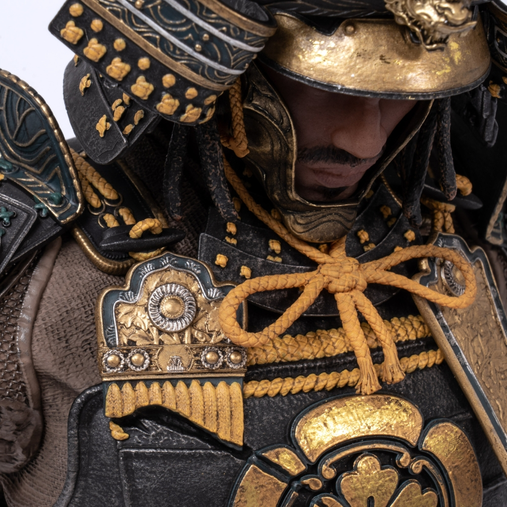 Ein Mann in detaillierter japanischer Samurai-Rüstung mit goldener und schwarzer Verzierung.